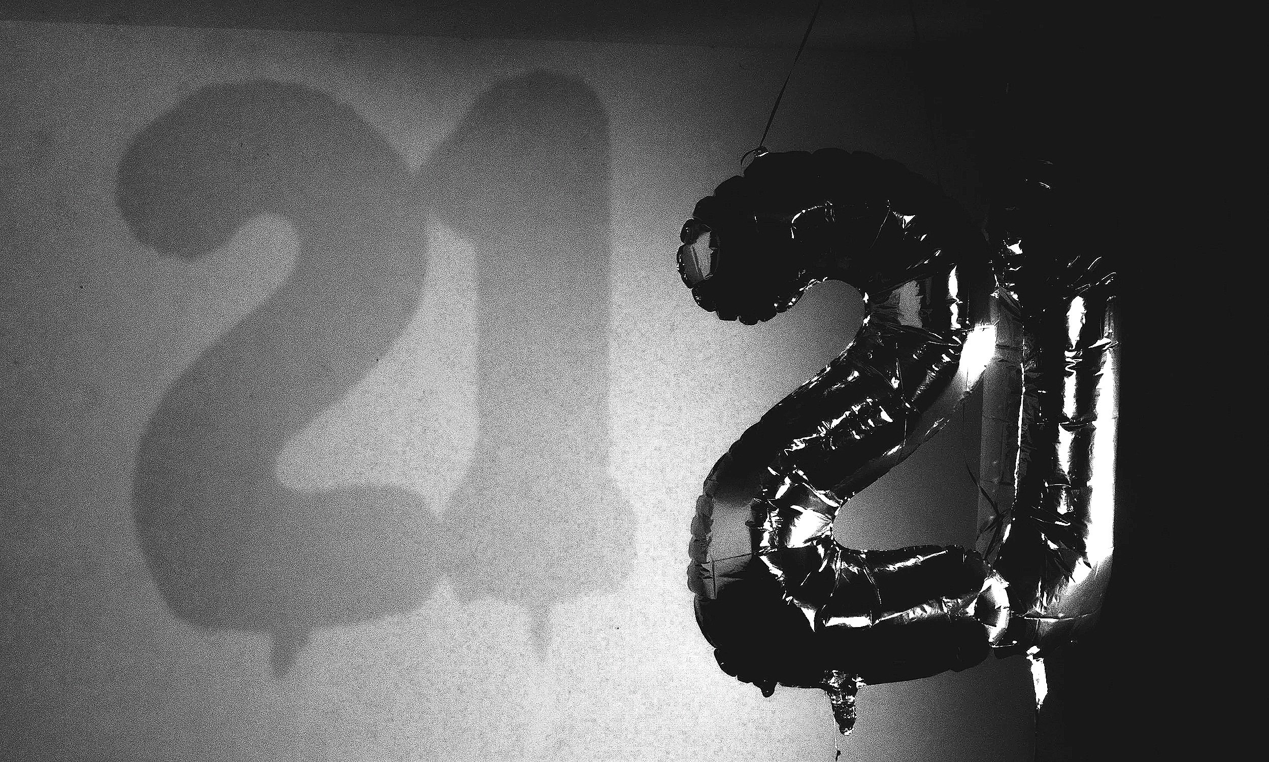 Black helium balloon letters spelling out 'LOVE' on a dark background.