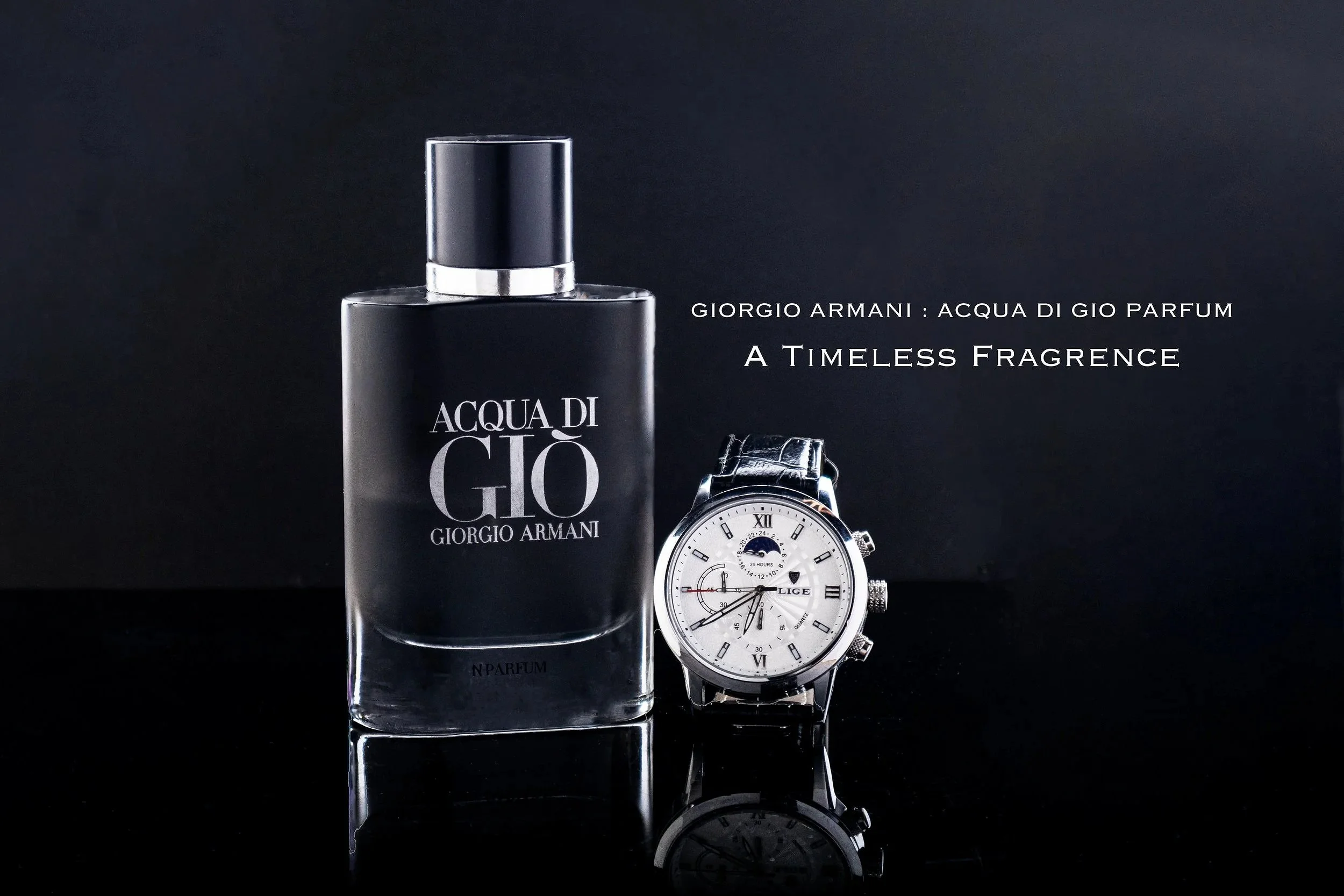 A bottle of Giorgio Armani Acqua di Giò perfume and a silver wristwatch with a white dial, black numbers, and multiple subdials, placed on a reflective black surface with a dark background.