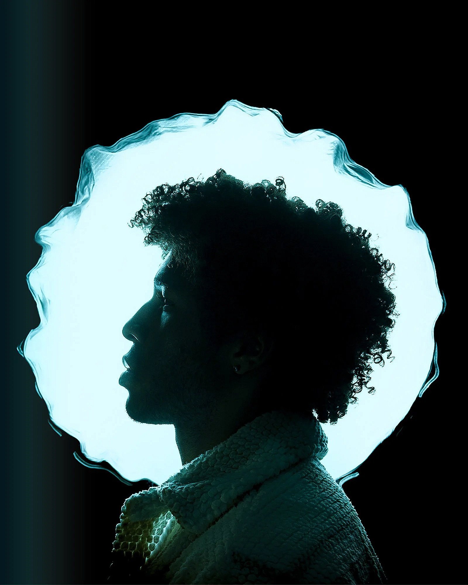 Silhouette of a person's profile with curly hair, surrounded by a glowing, jagged halo and a textured, scale-like garment against a dark background.