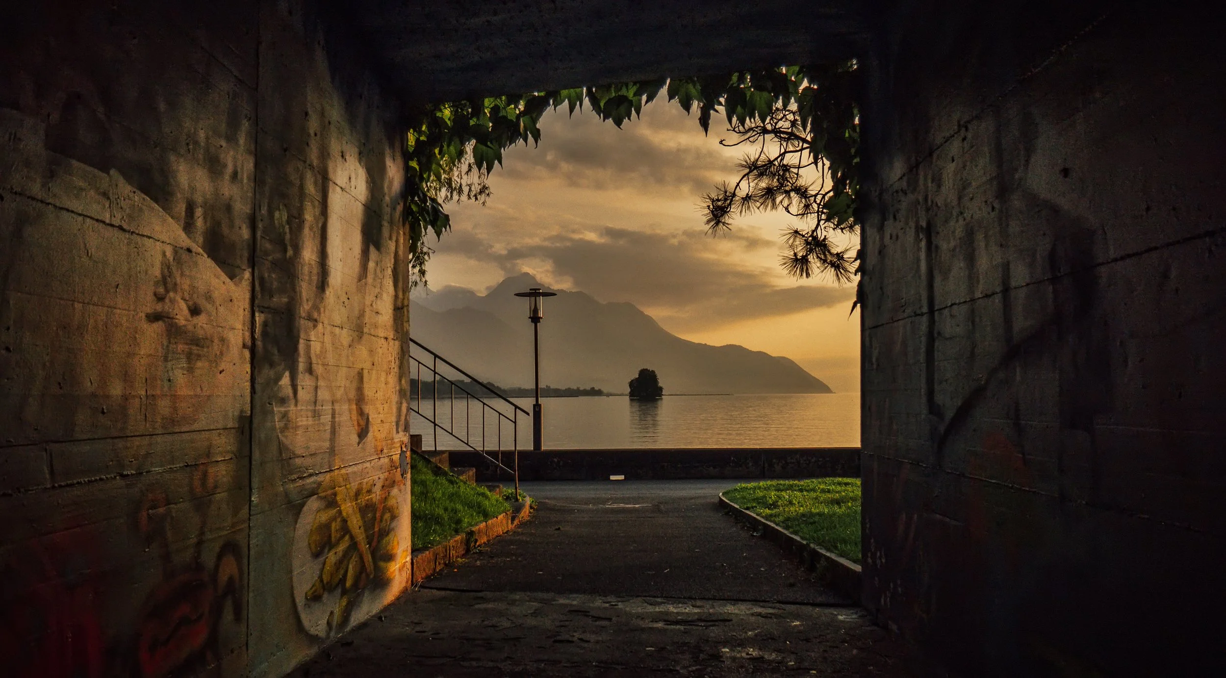 Atmosphärisches Landschaftsfoto mit Blick durch einen Durchgang auf das Meer und den Sonnenuntergang.