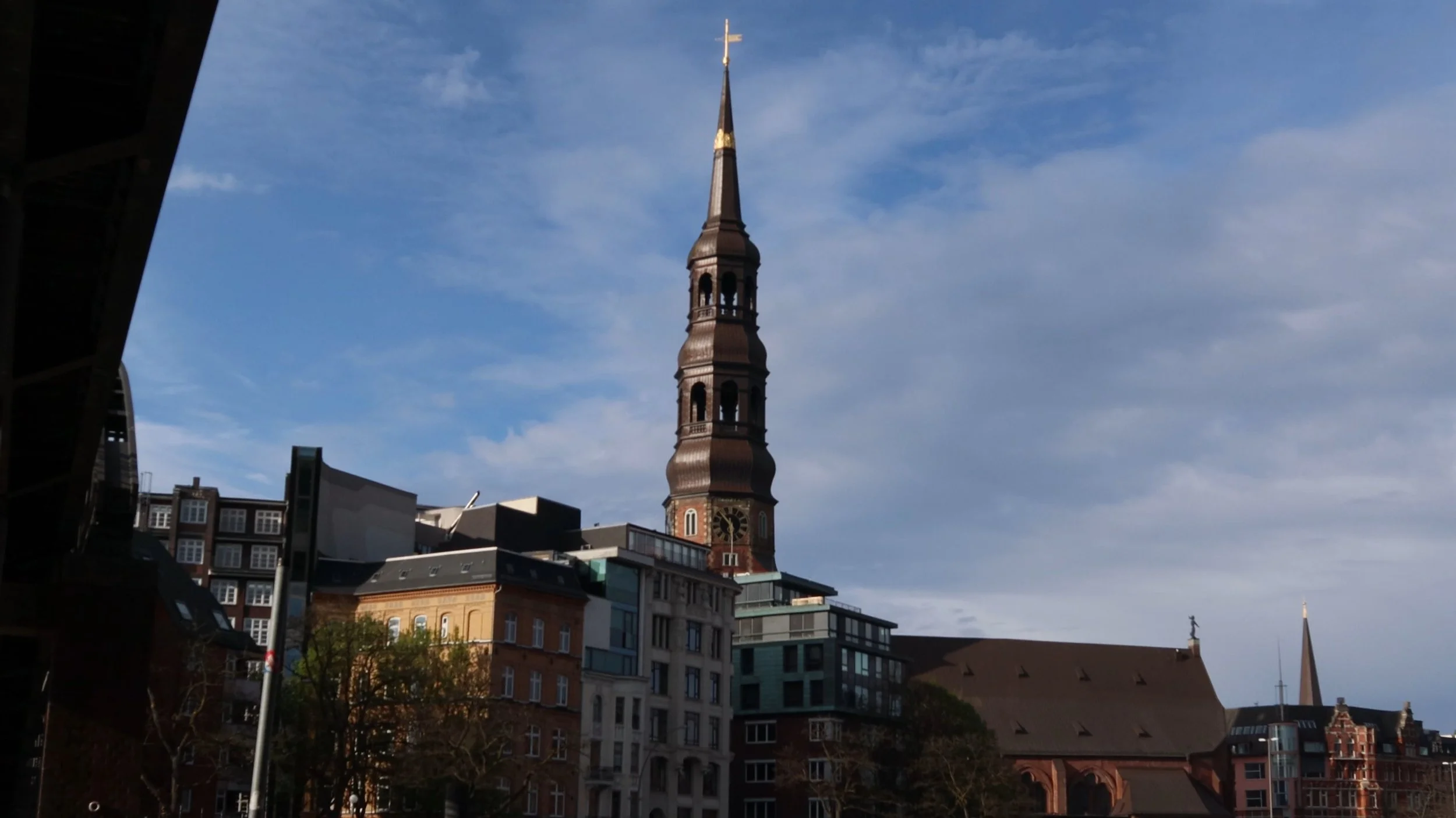 Cityscape with historic church steeple against blue sky and modern buildings in the background.