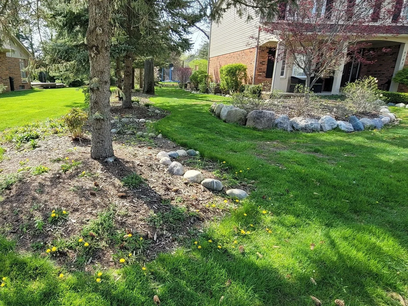 the before photo of a  residential landscape needing a cleanup, fresh mulch, sharp edging, trimmed beds, and some improved lawn care