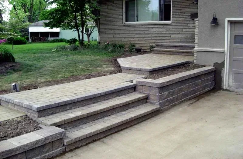 Newly built brick patio and steps for a raised backyard hardscape and outdoor living space.
