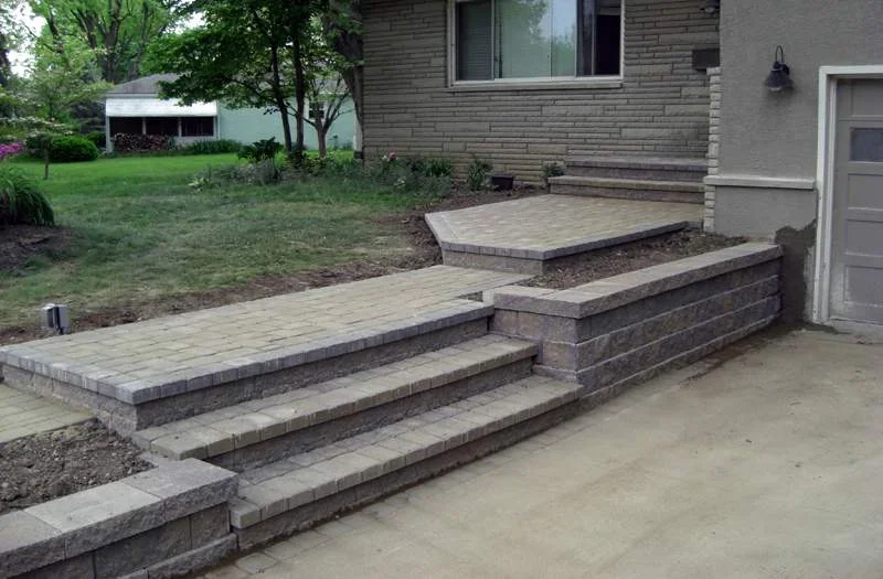 Newly built brick patio and steps for a raised backyard hardscape and outdoor living space.