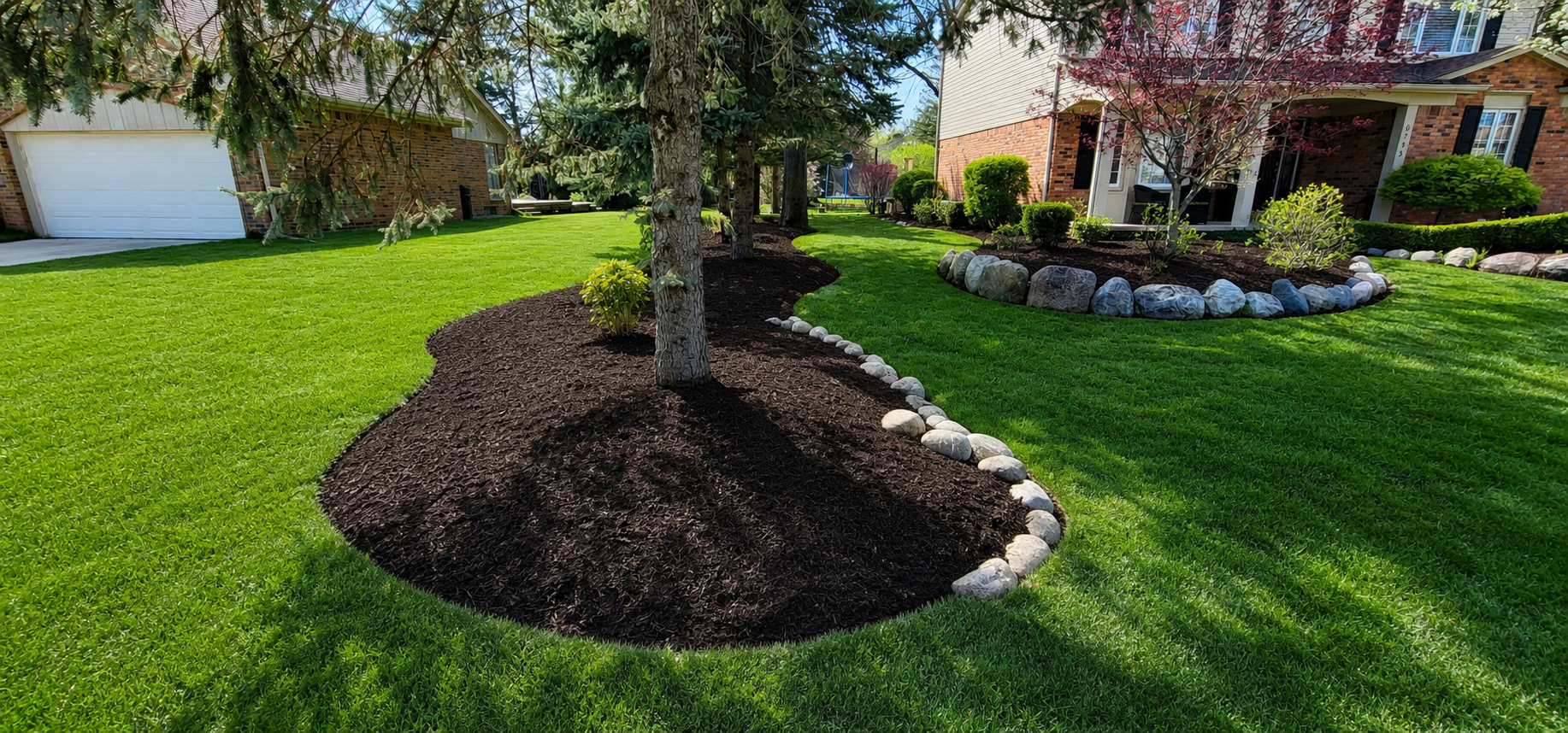 Professional lawn care and mulch installation with clean bed edging, healthy green grass, and refreshed landscape beds for a polished curb appeal upgrade.

