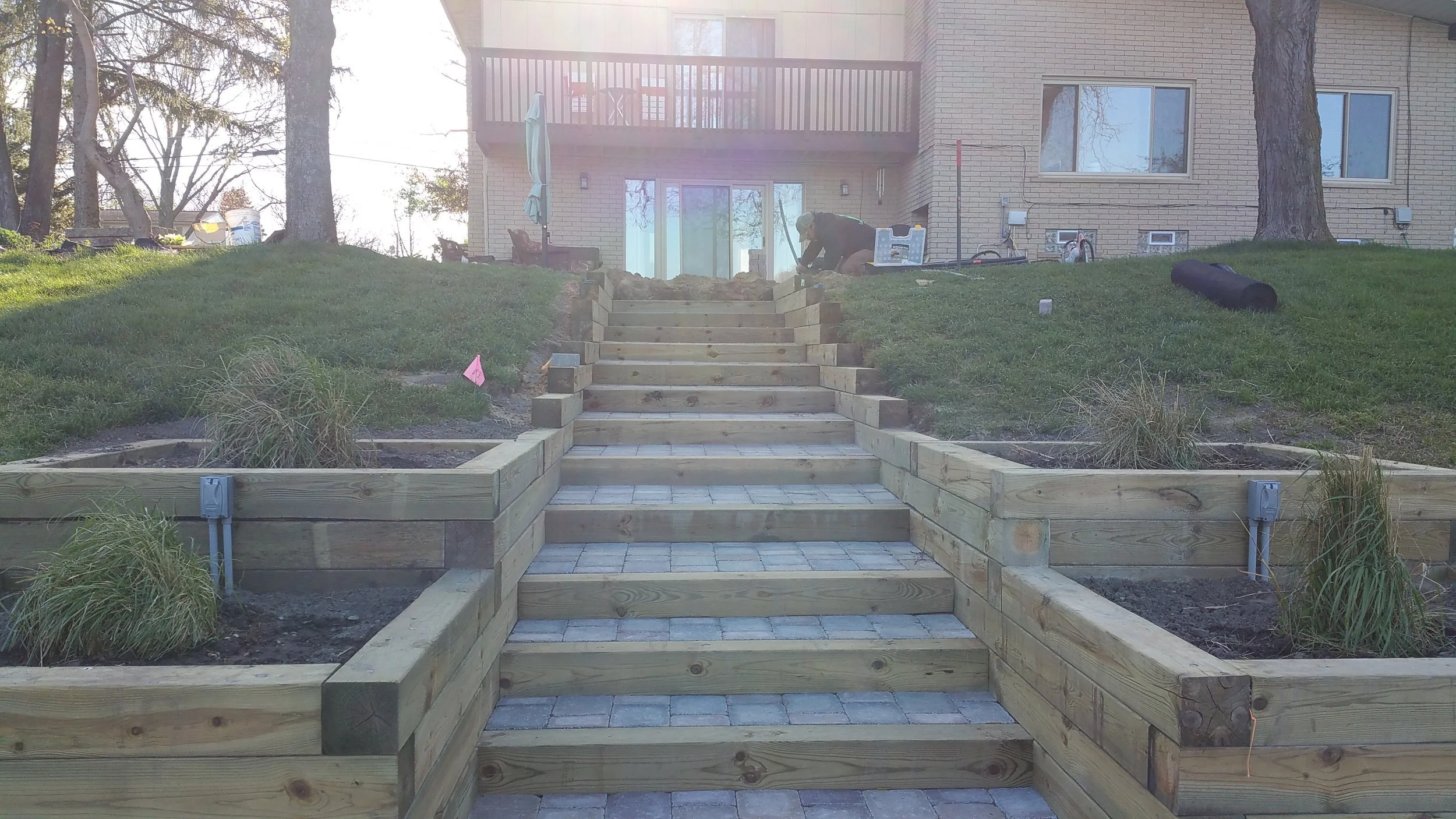 Outdoor wooden staircase construction for backyard access with landscape renovation work in progress.