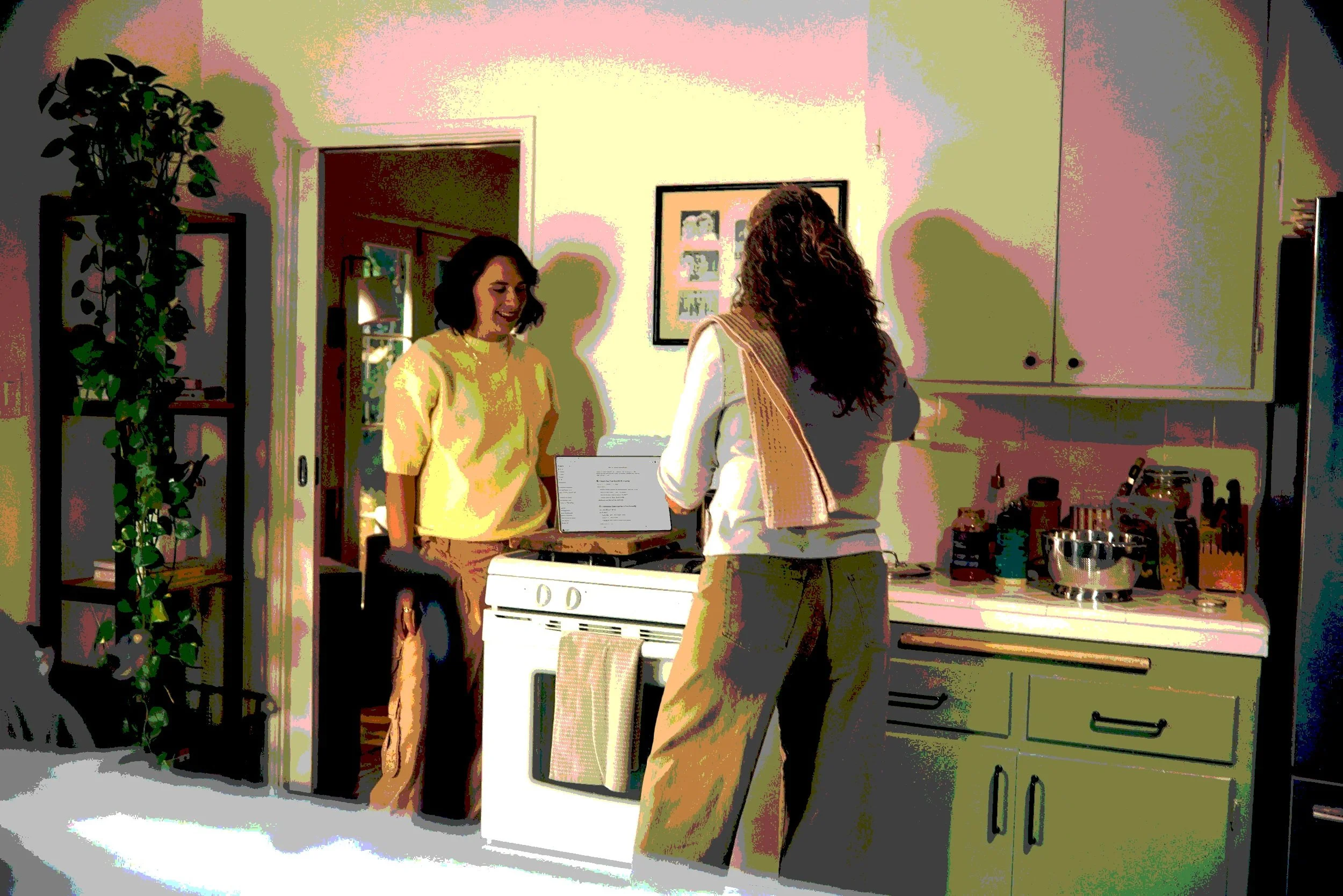 Two women in a home kitchen reviewing research notes on a laptop, illustrating field research with a design firm