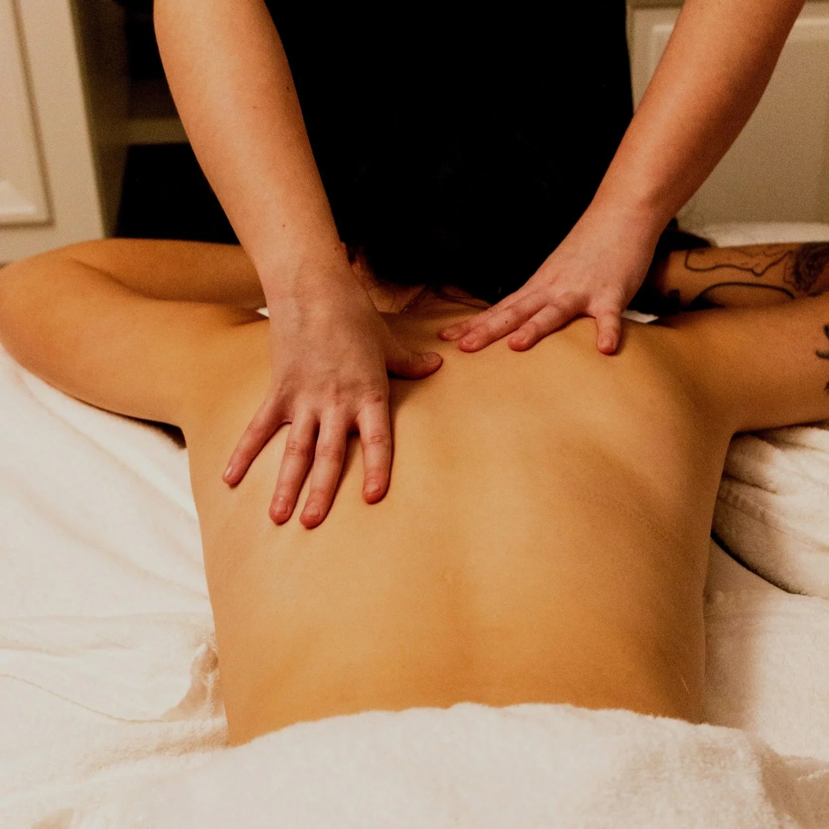A person receiving a massage while lying on their stomach on a massage table.
