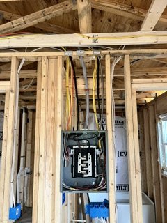 Electrical panel installed inside a wooden framed wall of a building under construction.