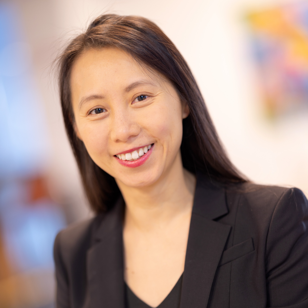 A smiling young woman with straight dark hair wearing a black blazer.