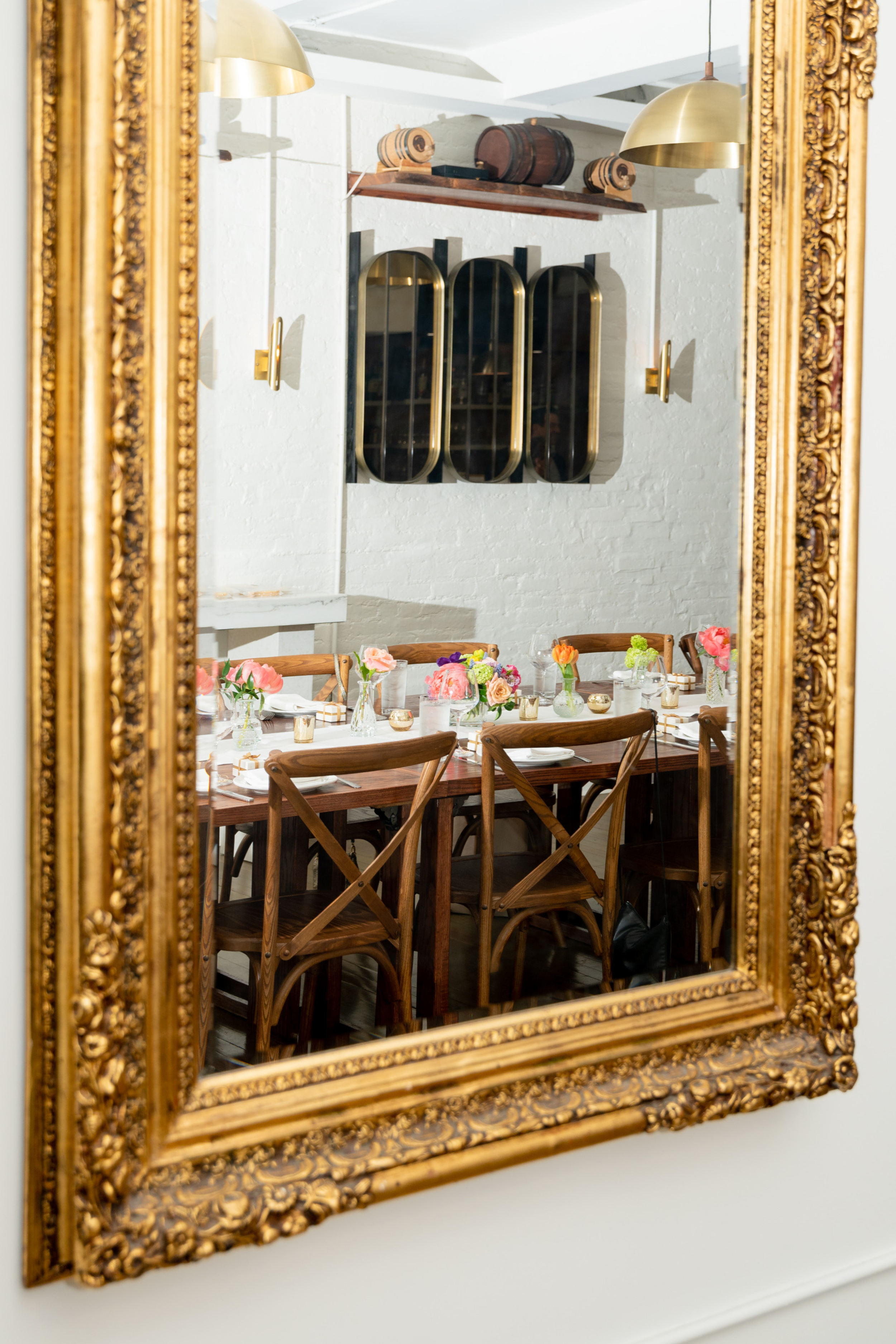 Elegant wedding reception design with floral centerpieces and curated tablescape reflected in a vintage gold mirror
