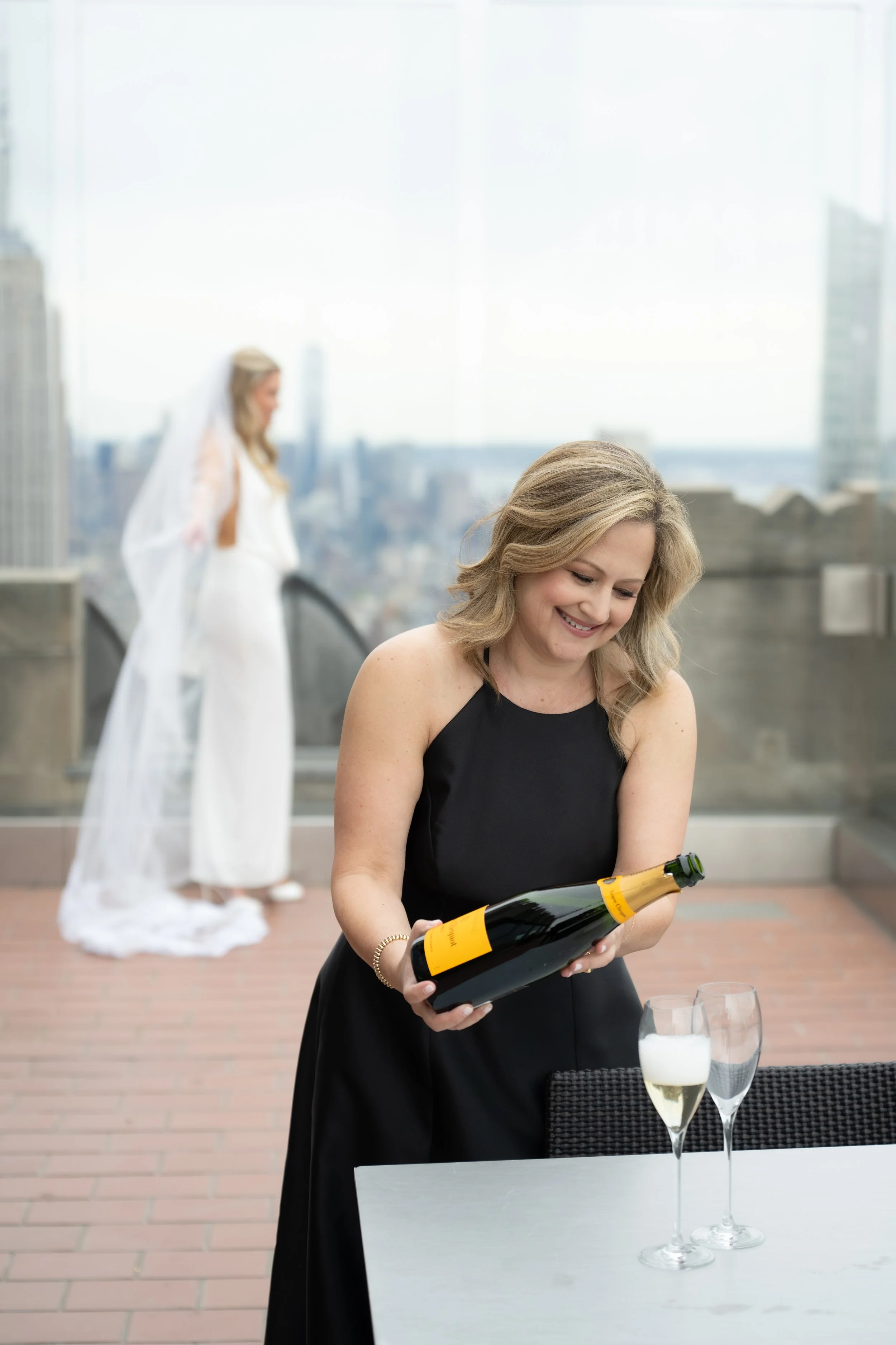 Alisha Hope opening champagne for a bride during a luxury rooftop wedding celebration in New York City