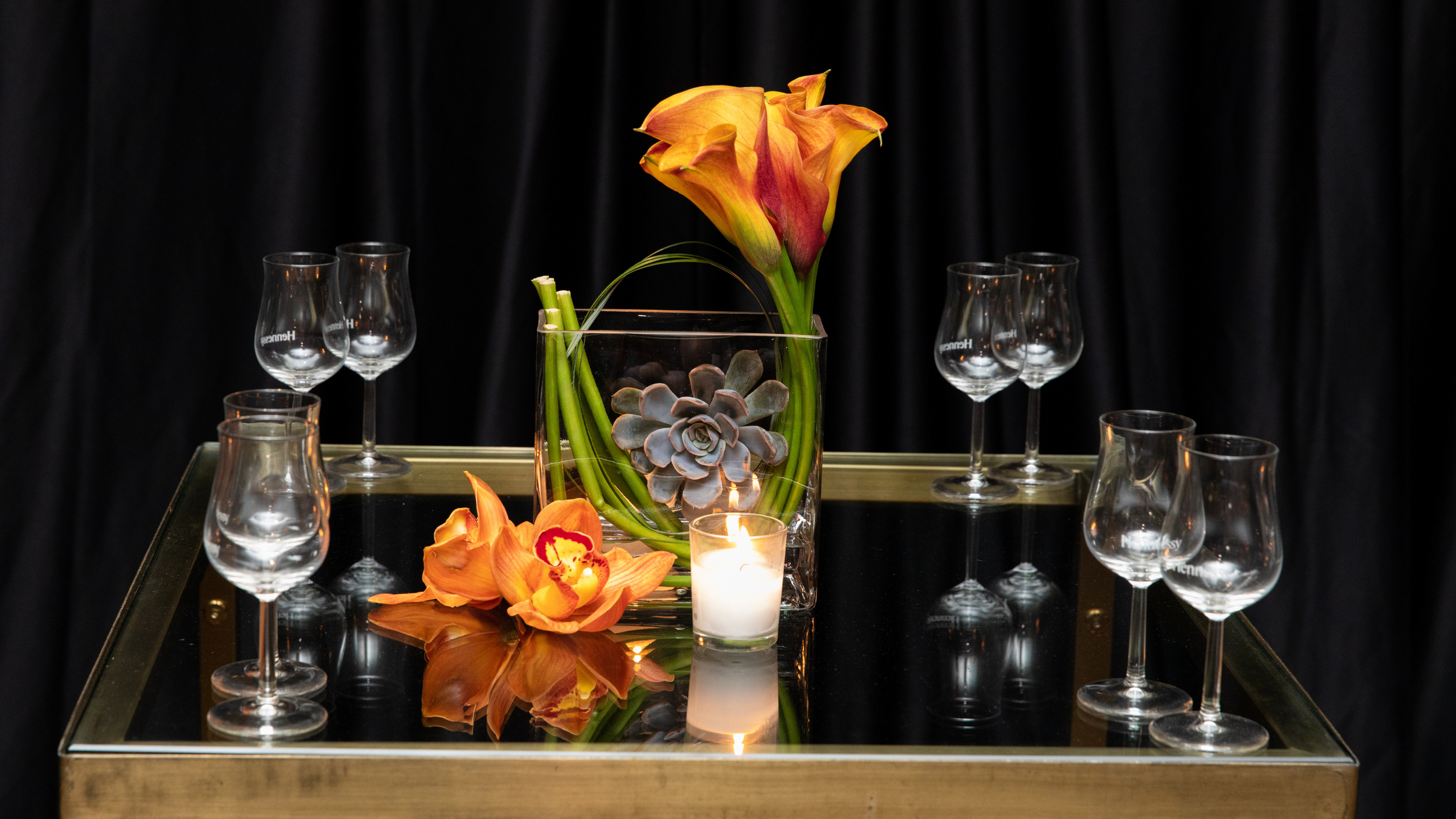Modern event tablescape featuring orange calla lilies, candlelight, and elevated floral design for a luxury celebration