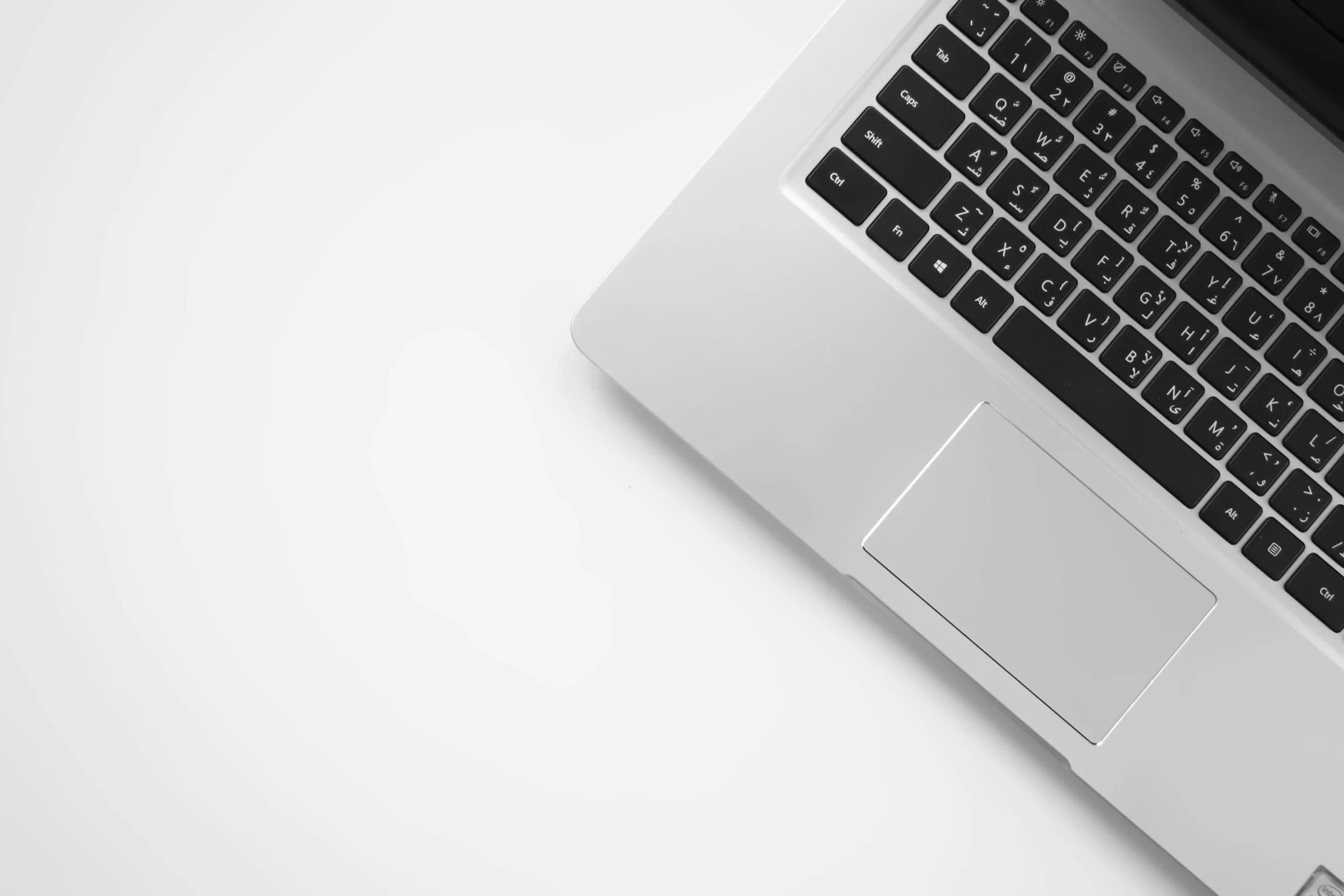 Close-up of a silver laptop keyboard on a white surface.