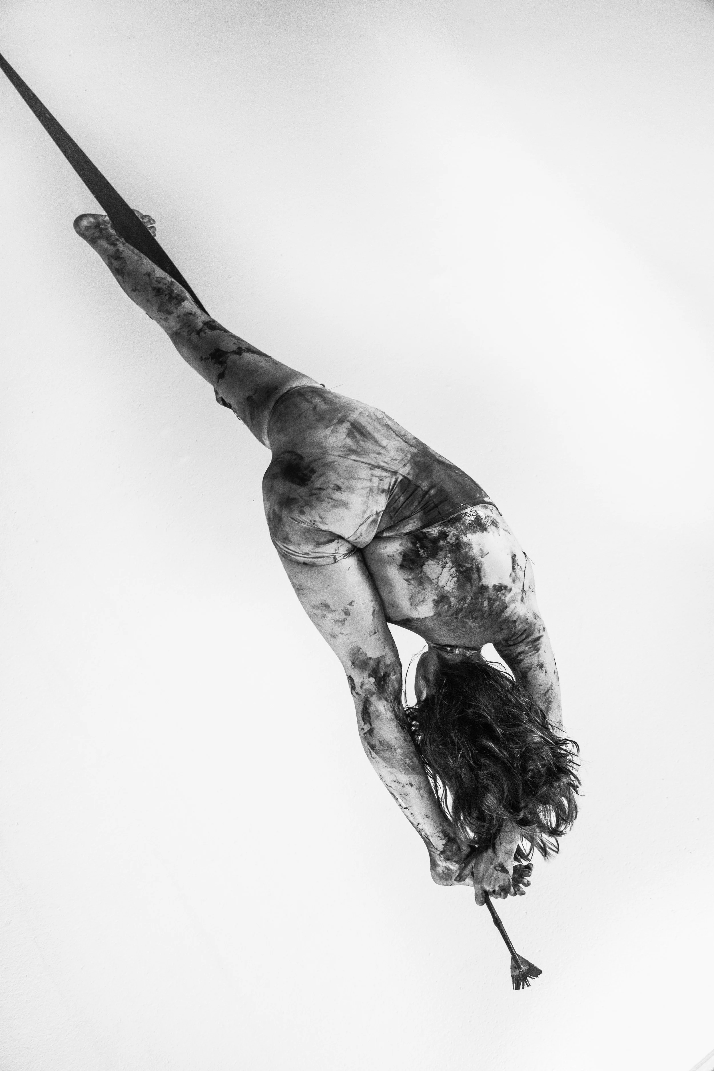 Una bailarina de ballet en posición de equilibrio, inclinada con las manos tocando el suelo y la cabeza hacia abajo. La imagen es en blanco y negro, con fondo blanco.