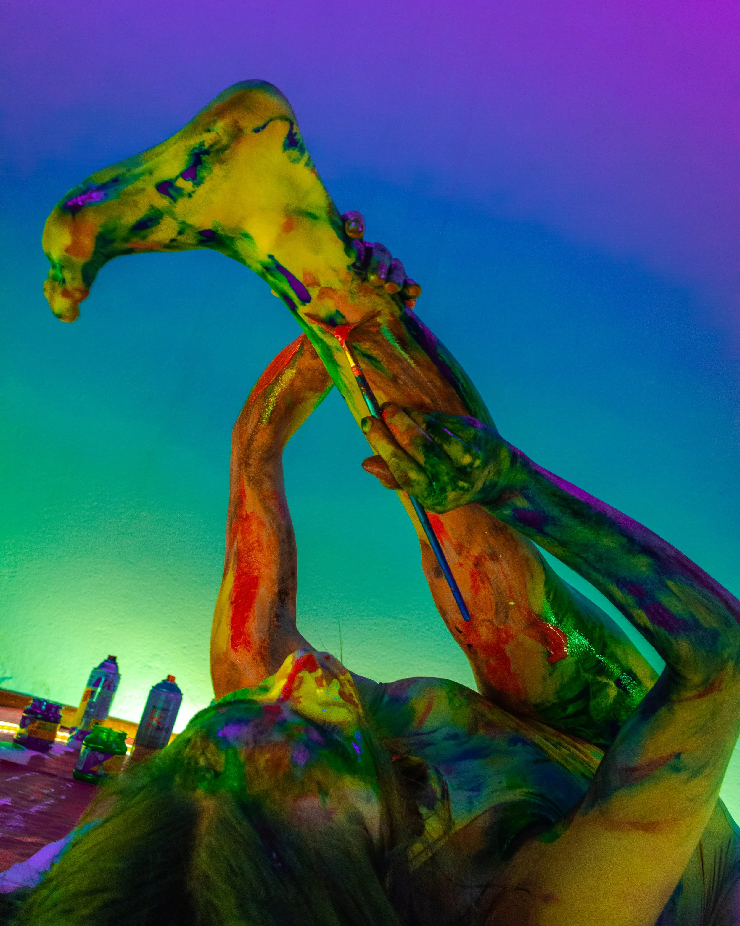Estatua de una mano sosteniendo una brocha, con colores vibrantes y fondo de ciudad y cielo