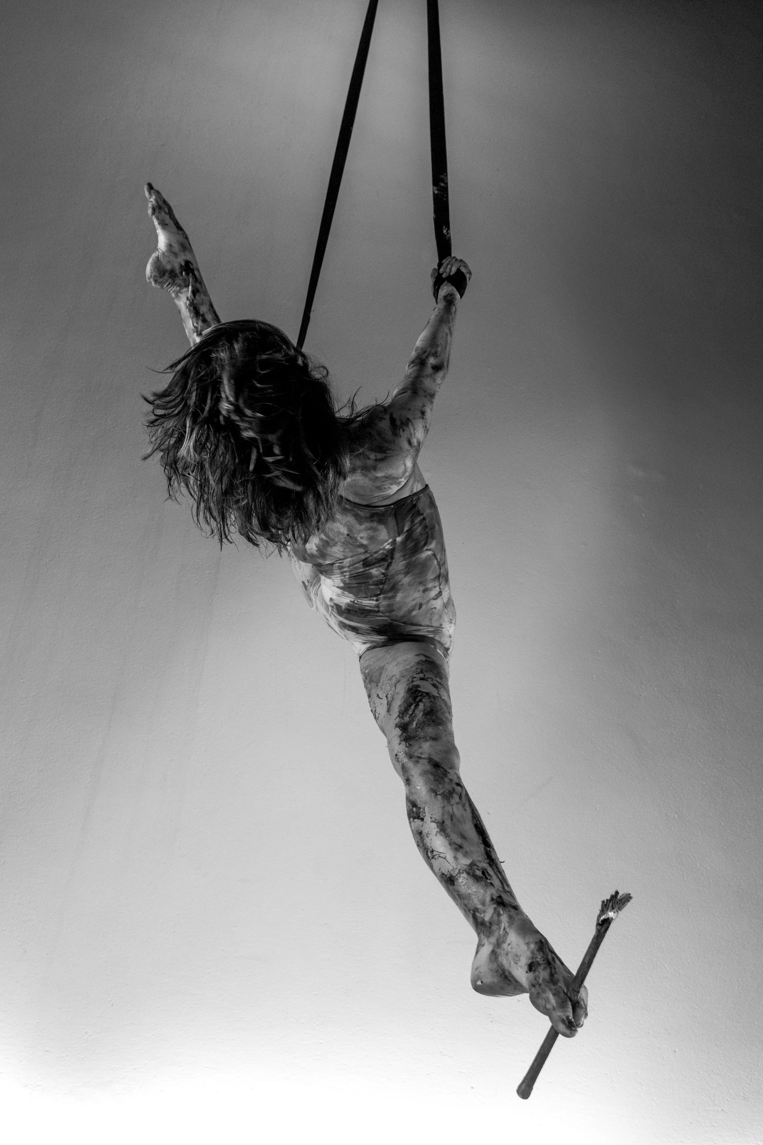 Escultura de una figura humana en una pose de equilibrio, sosteniendo una barra y con el cuerpo en posición invertida, en un espacio con paredes lisas.