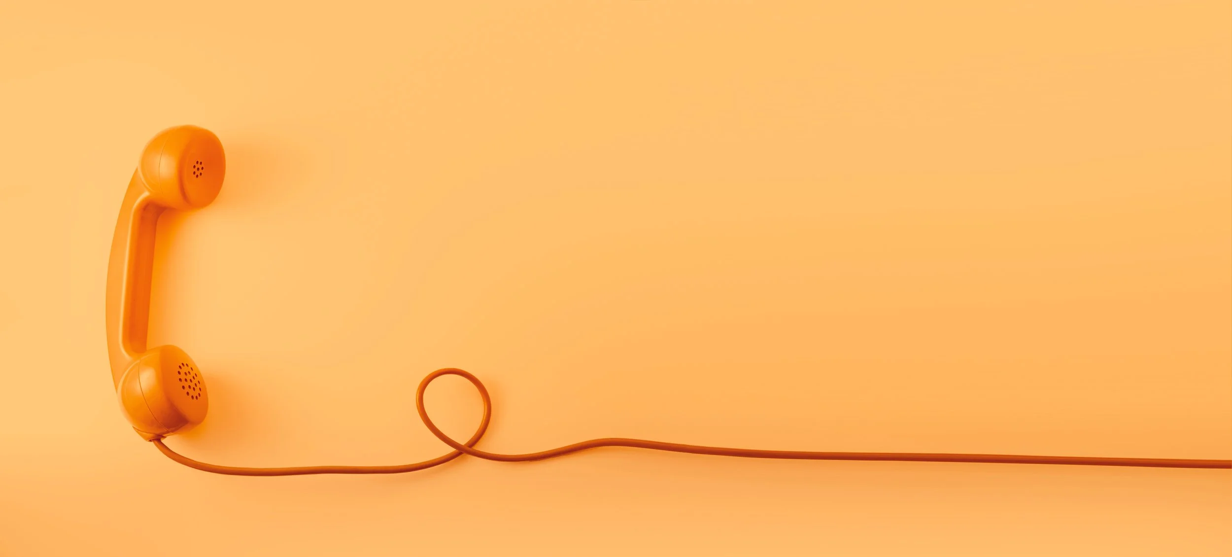 An orange telephone handset connected by a cord, resting on an orange background.