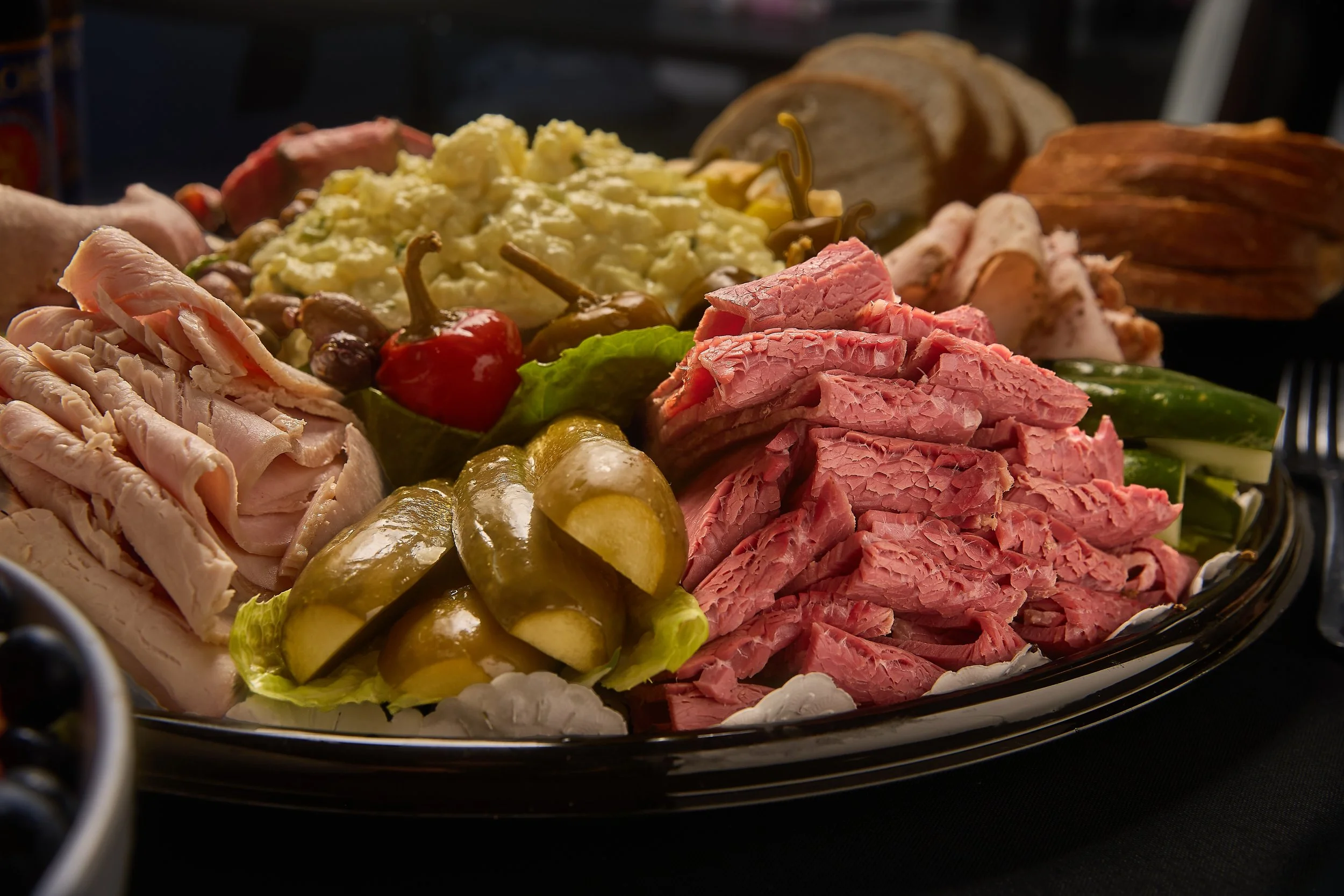 Assorted deli meats, cheeses, and vegetables on a platter.