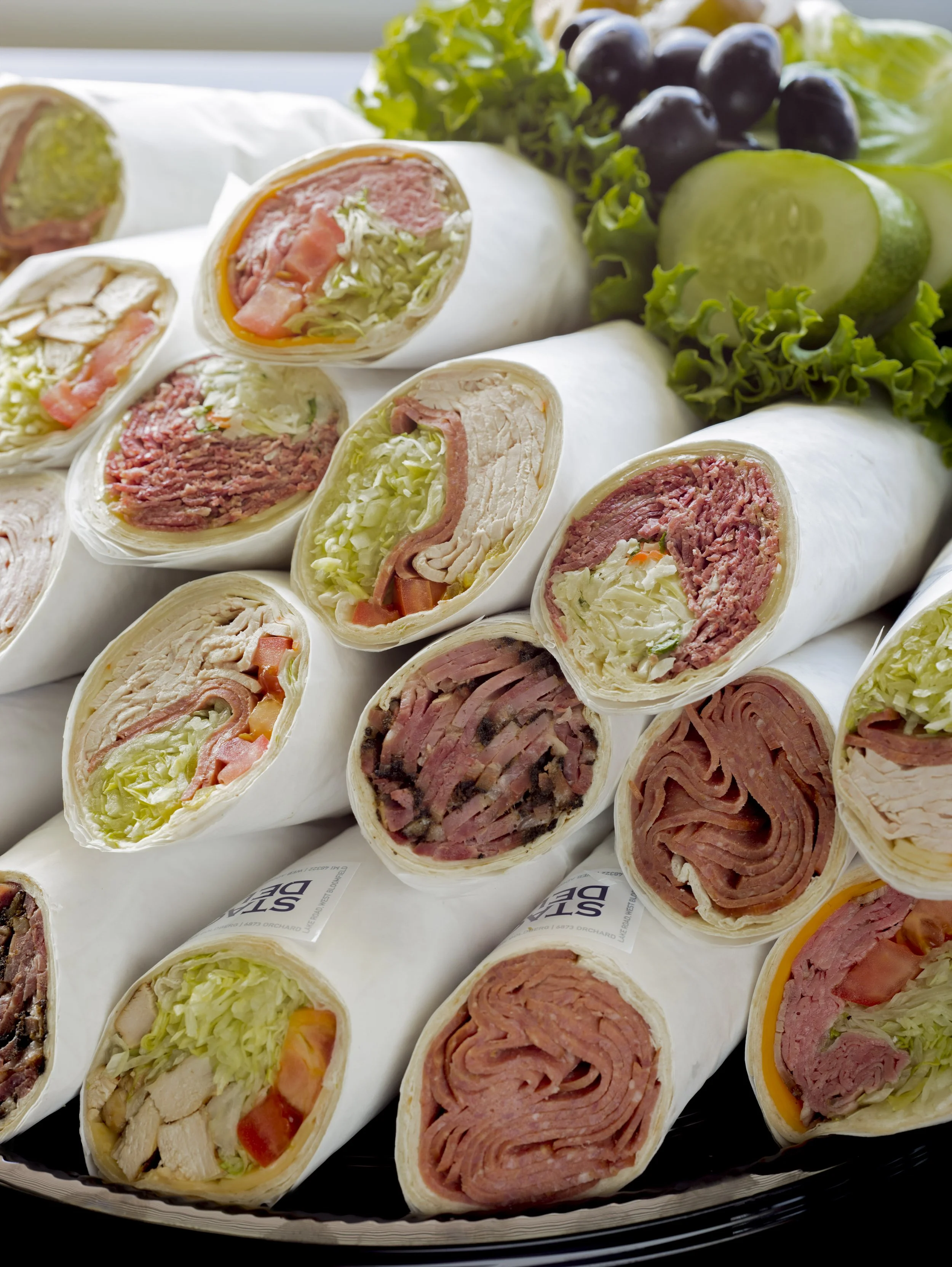 catering tray of rolled deli wrapped sandiwches