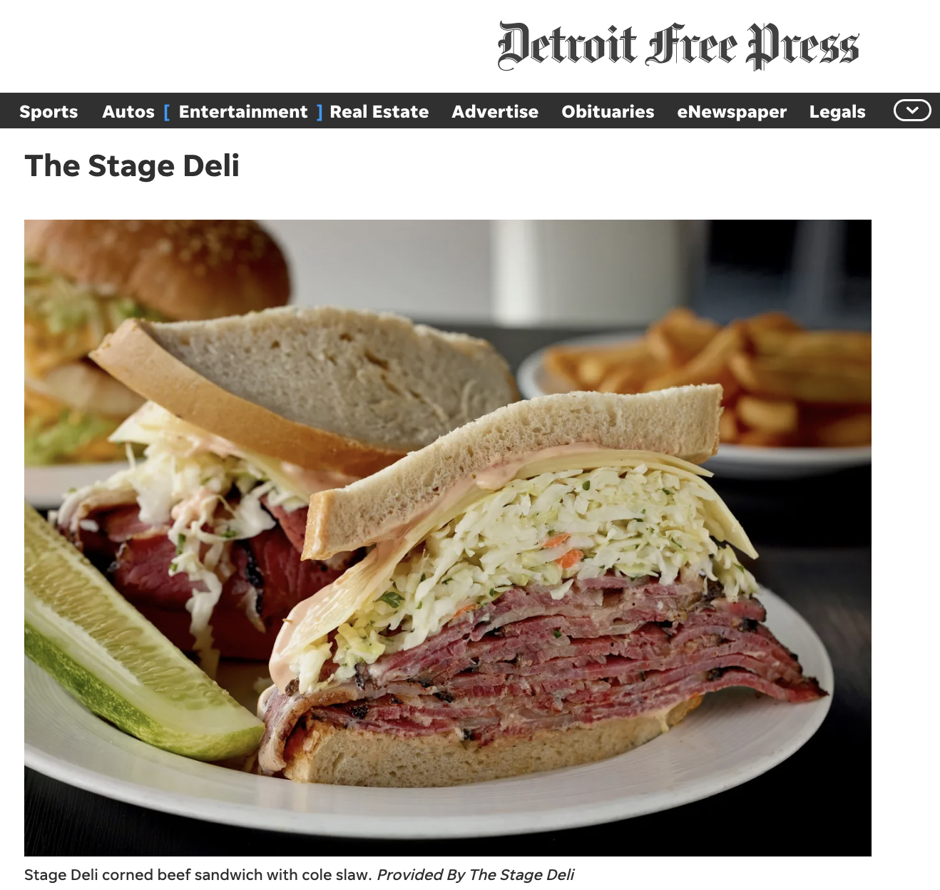 A corned beef sandwich with cole slaw on white bread, served with pickles and a side of fries.