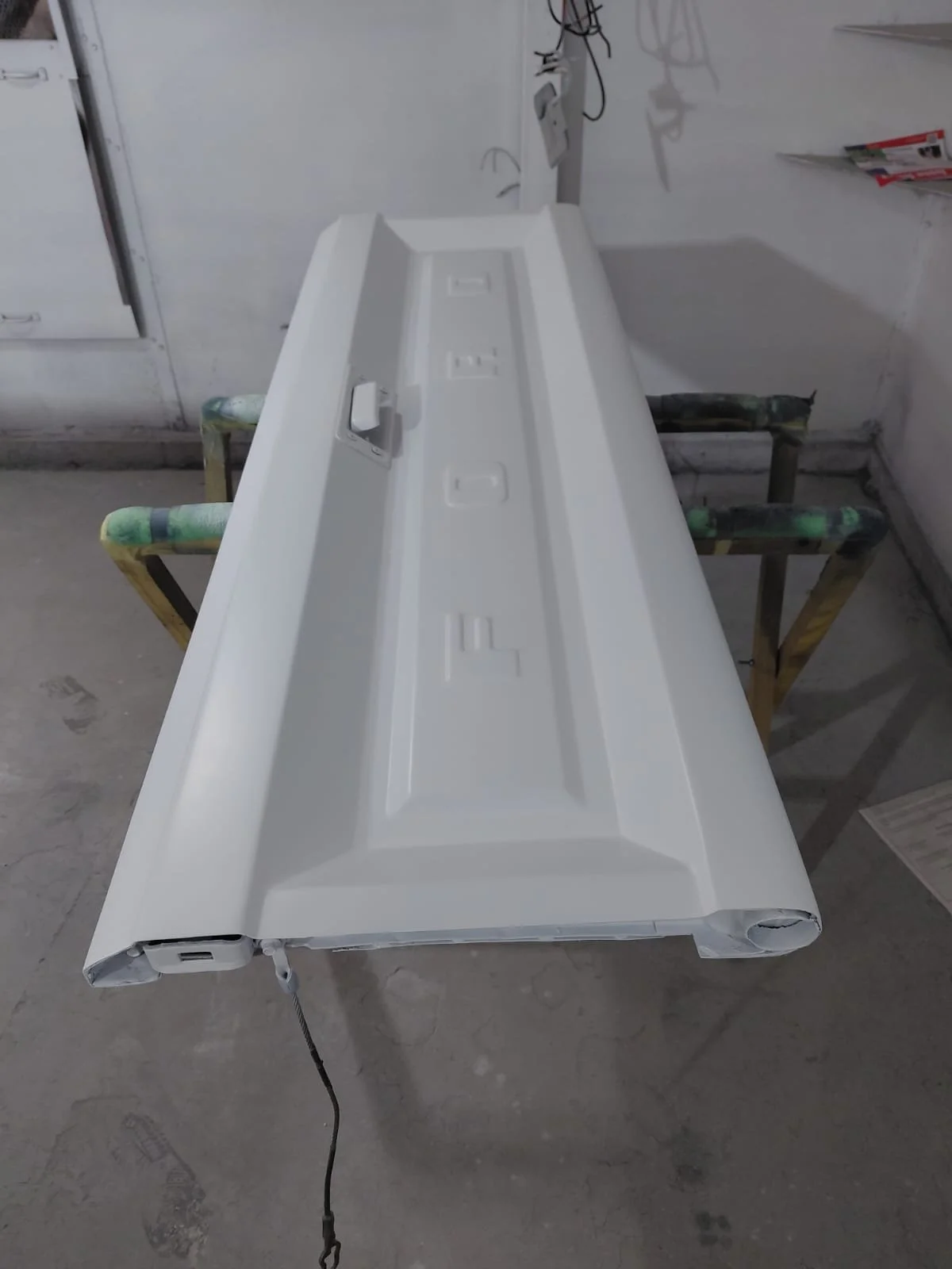 Superficie blanca en una mesa de trabajo con cables y herramientas a su alrededor, ubicada en un taller o área de construcción.