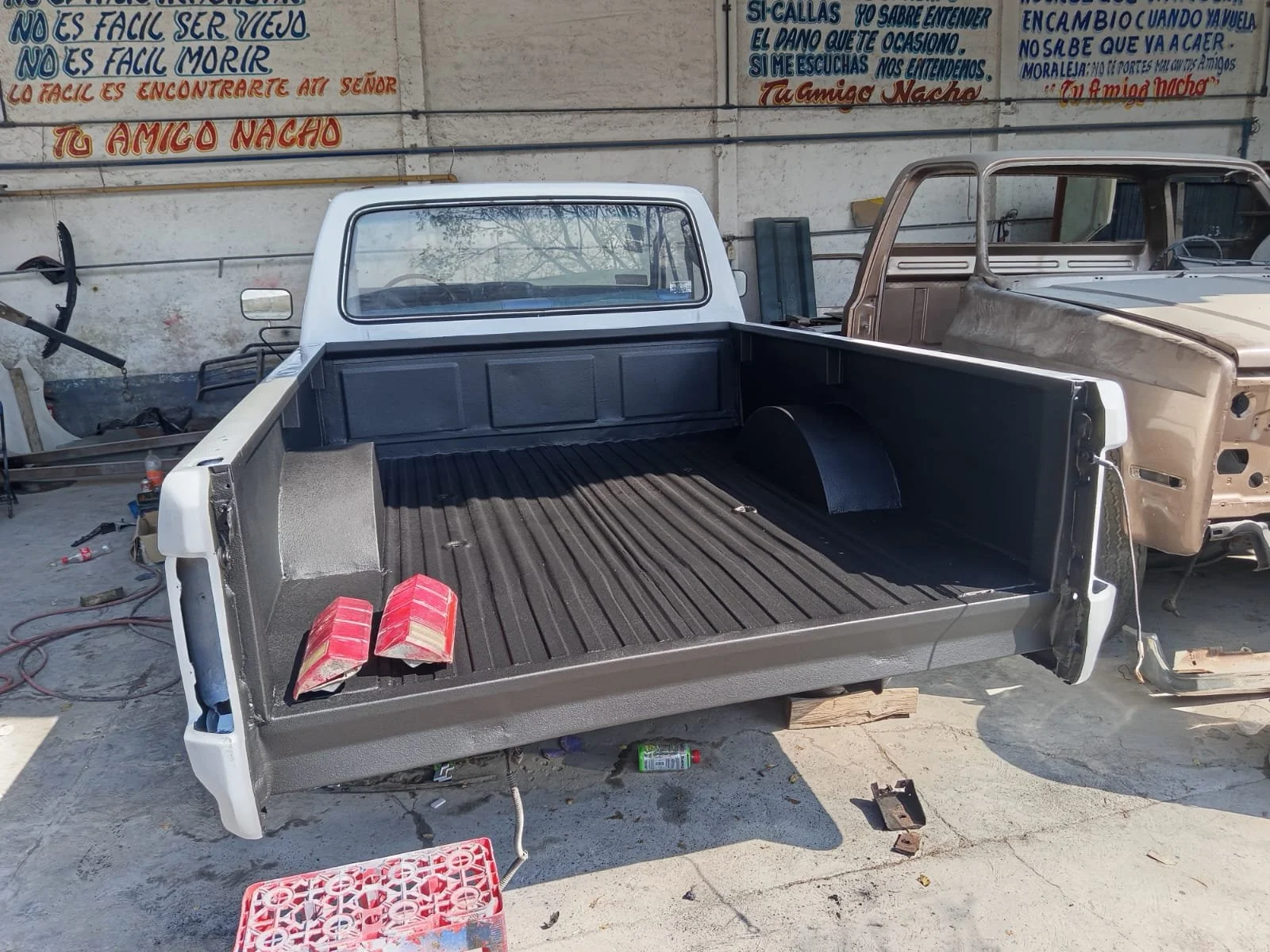 Camionetas en proceso de restauración en un taller, con partes y herramientas esparcidas alrededor.