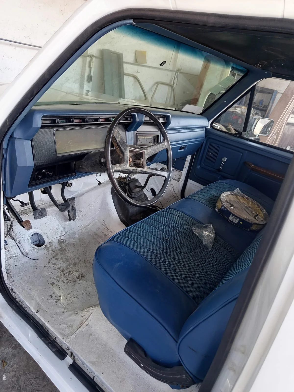 Interior de una camioneta antigua con tablero y volante desgastados y asientos azules