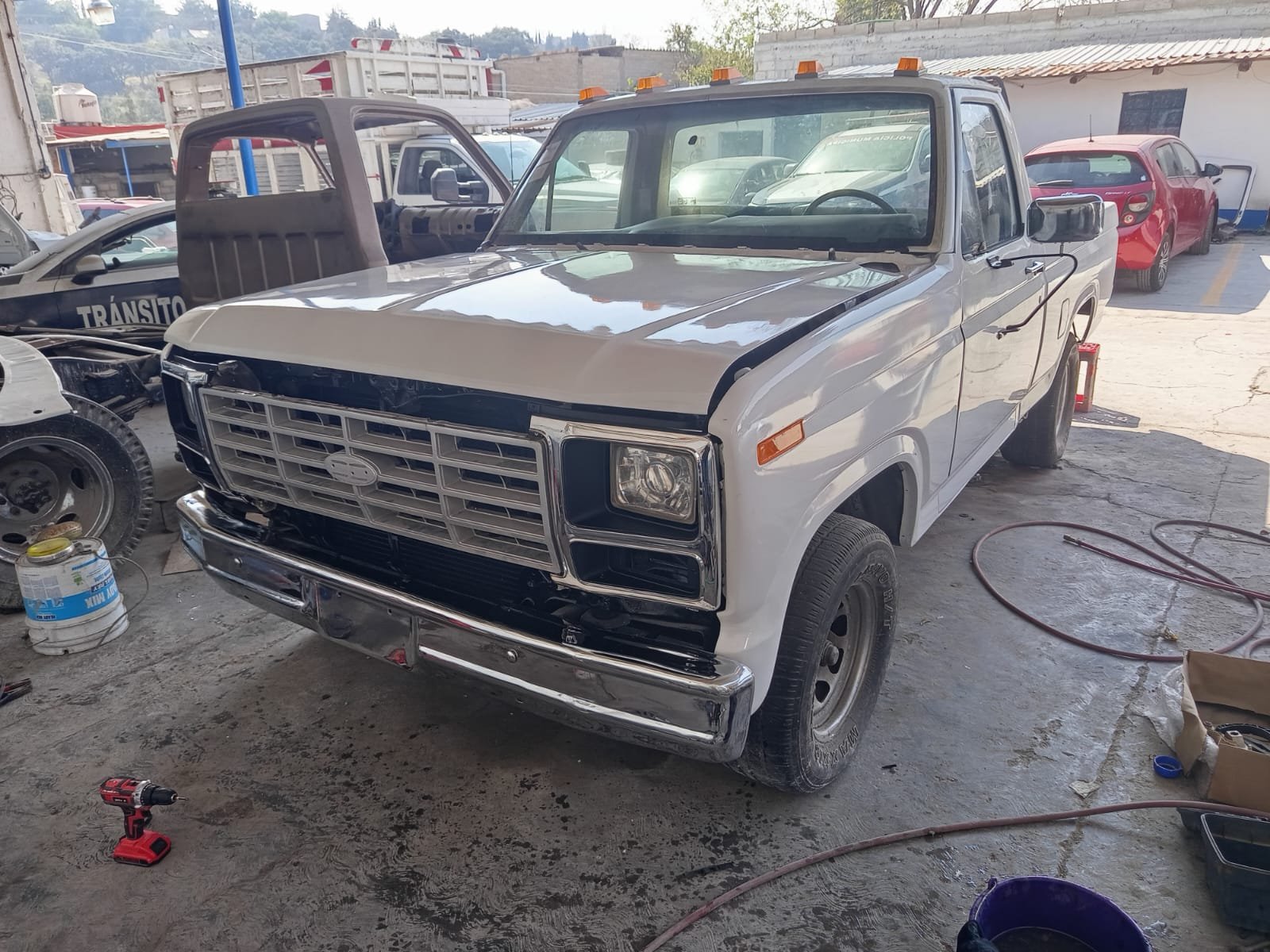 Camioneta en reparación en un taller, con herramientas y partes alrededor.