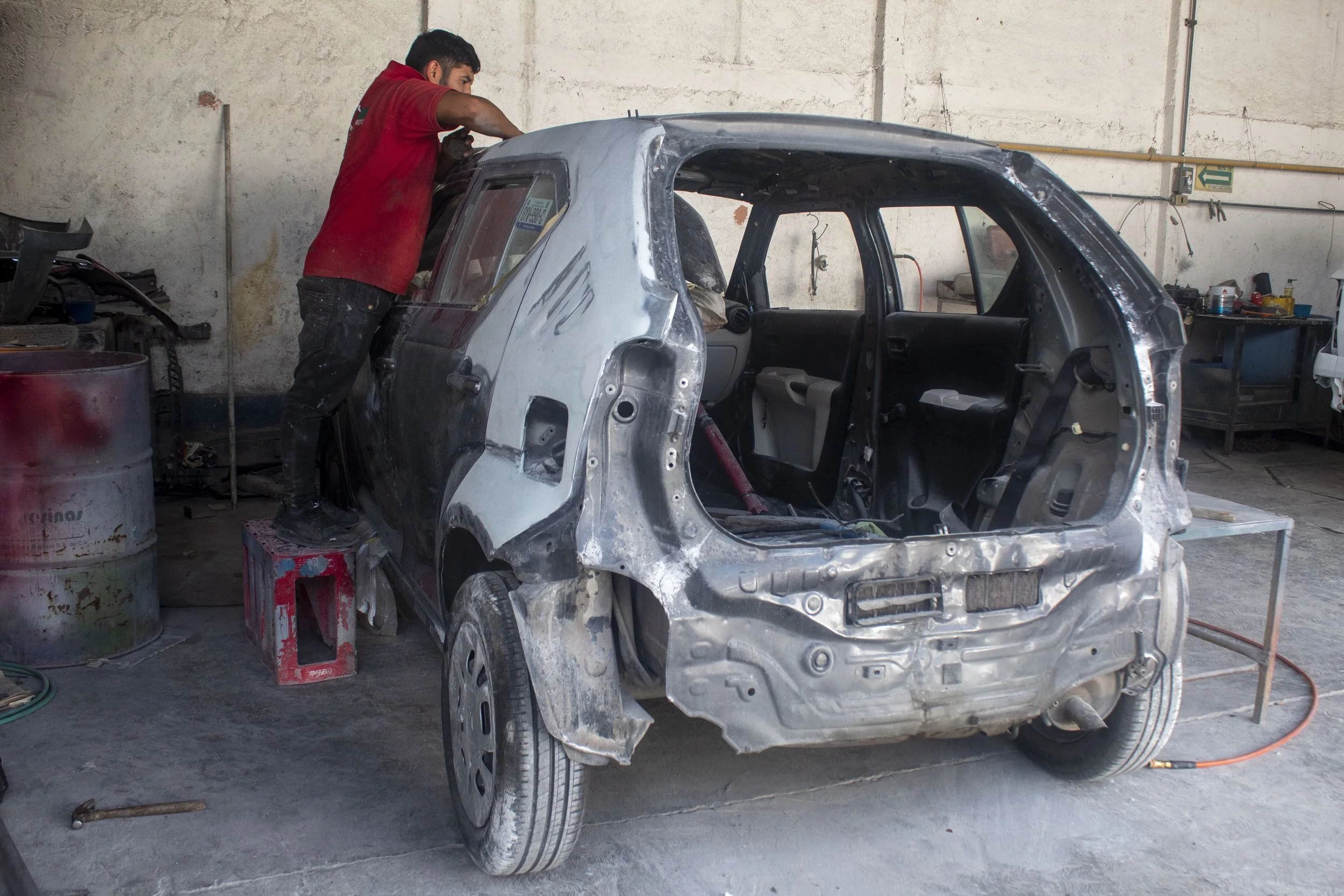 Un mecánico trabajando en la carrocería de un coche en un taller de reparación de autos.