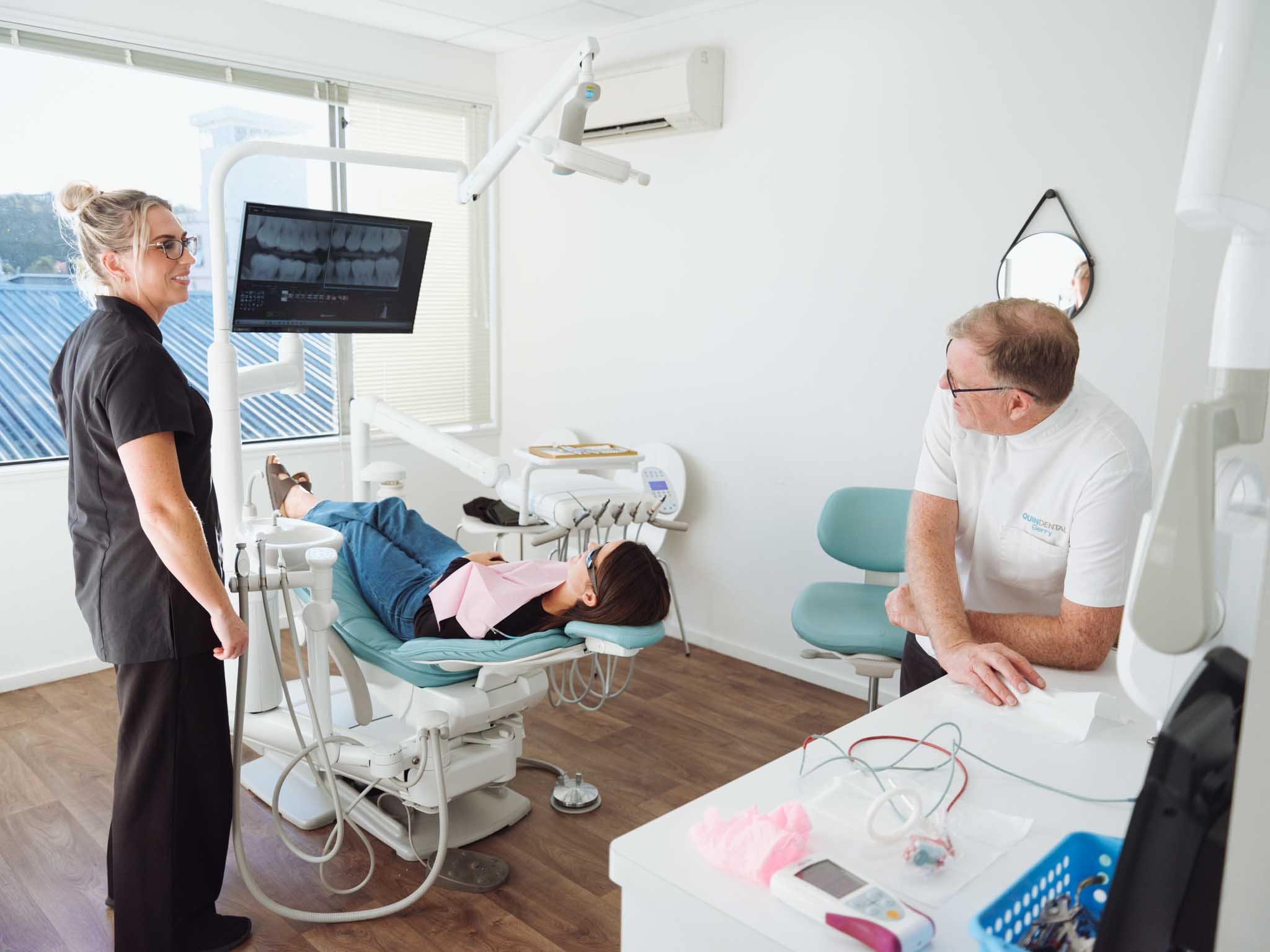 Gerry Quin and dental assistant review x-rays with a patient during dental exam at Quin Dental in Nelson, New Zealand.