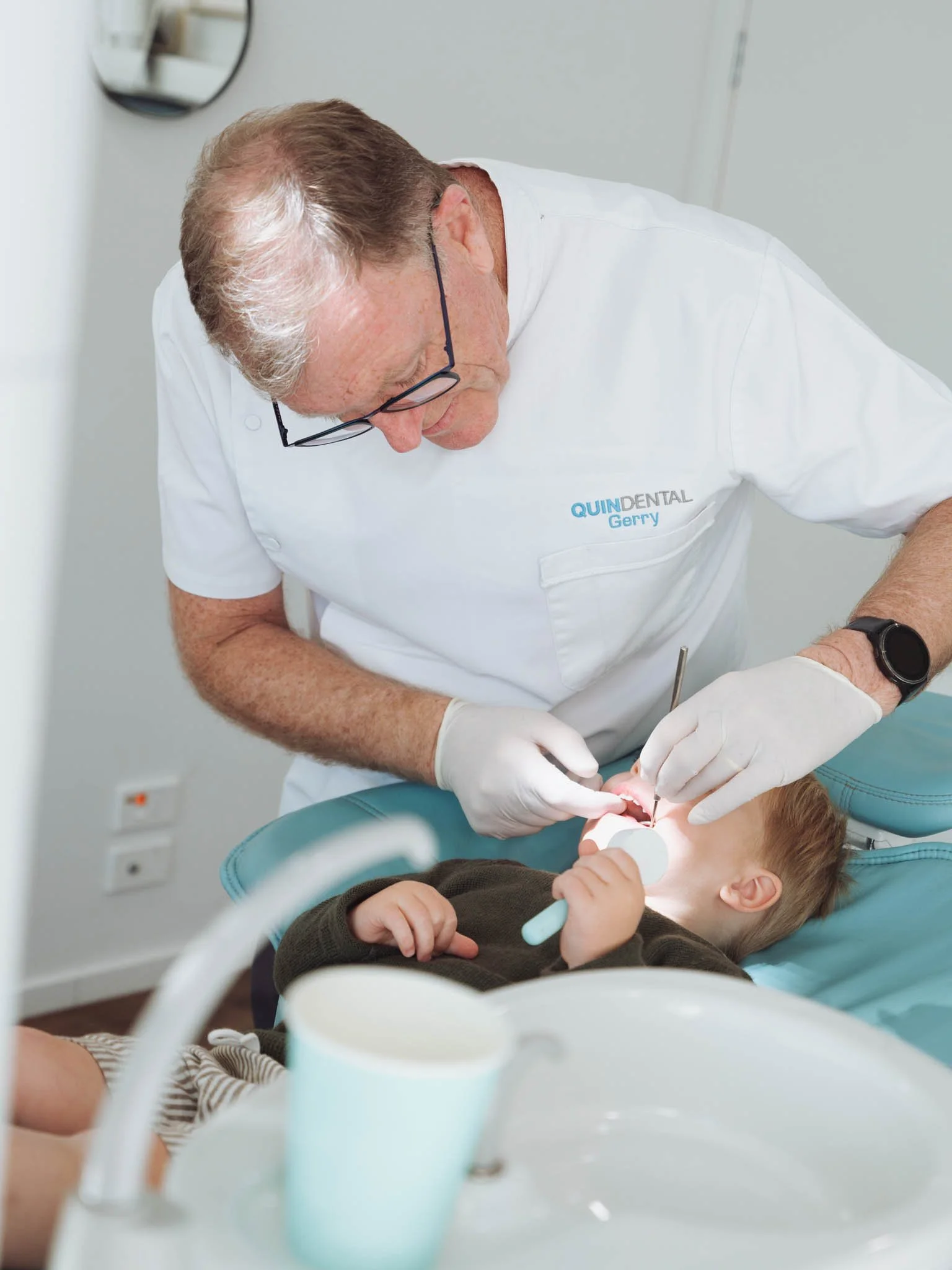 Gerry Quin, performs dental check-up on a young child lying in a dental chair at Quin Dental, Nelson, New Zealand