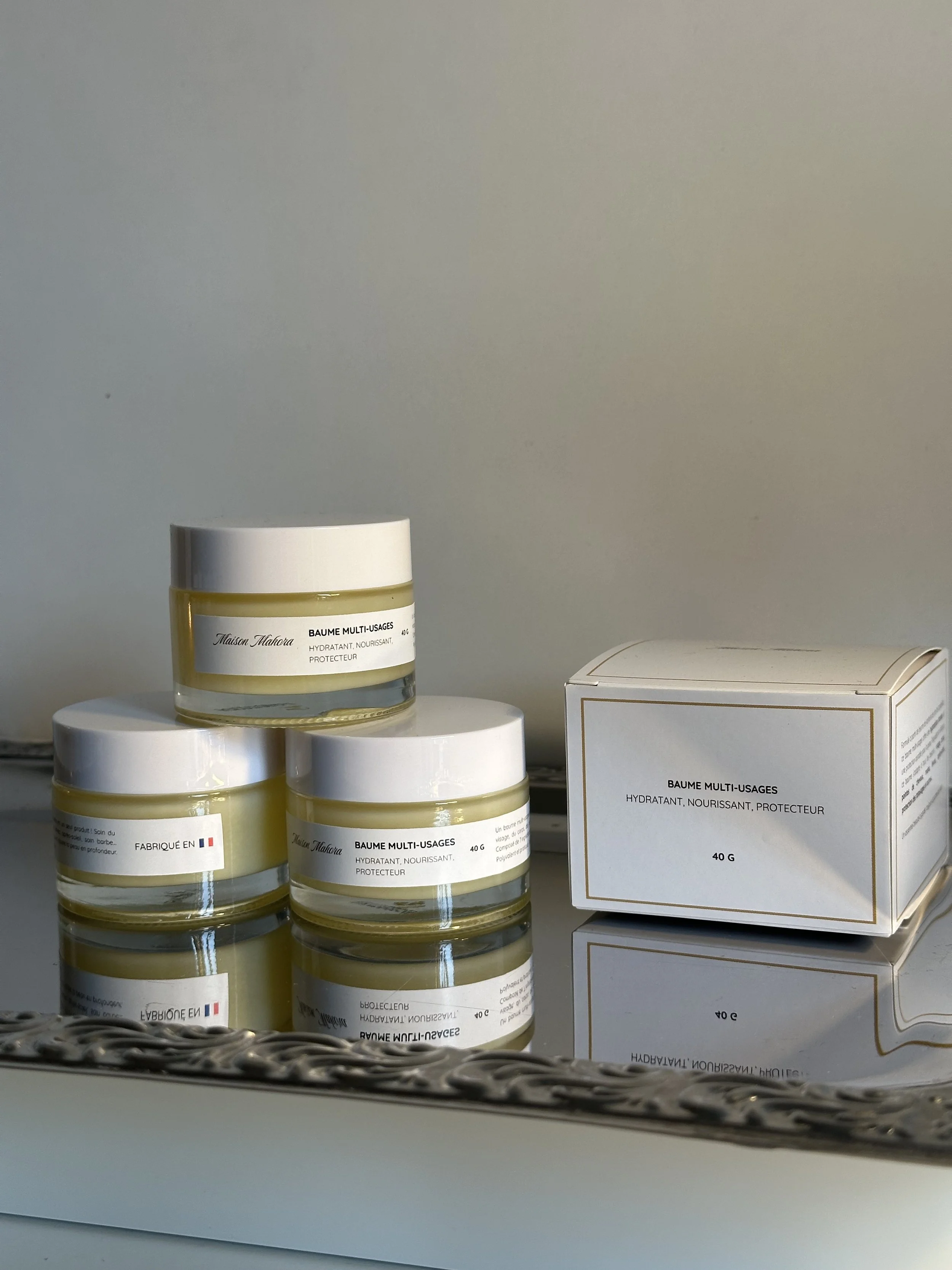 Boîtes et pots de crème hydratante appelée 'Baume Multi-Usages' avec description en français.