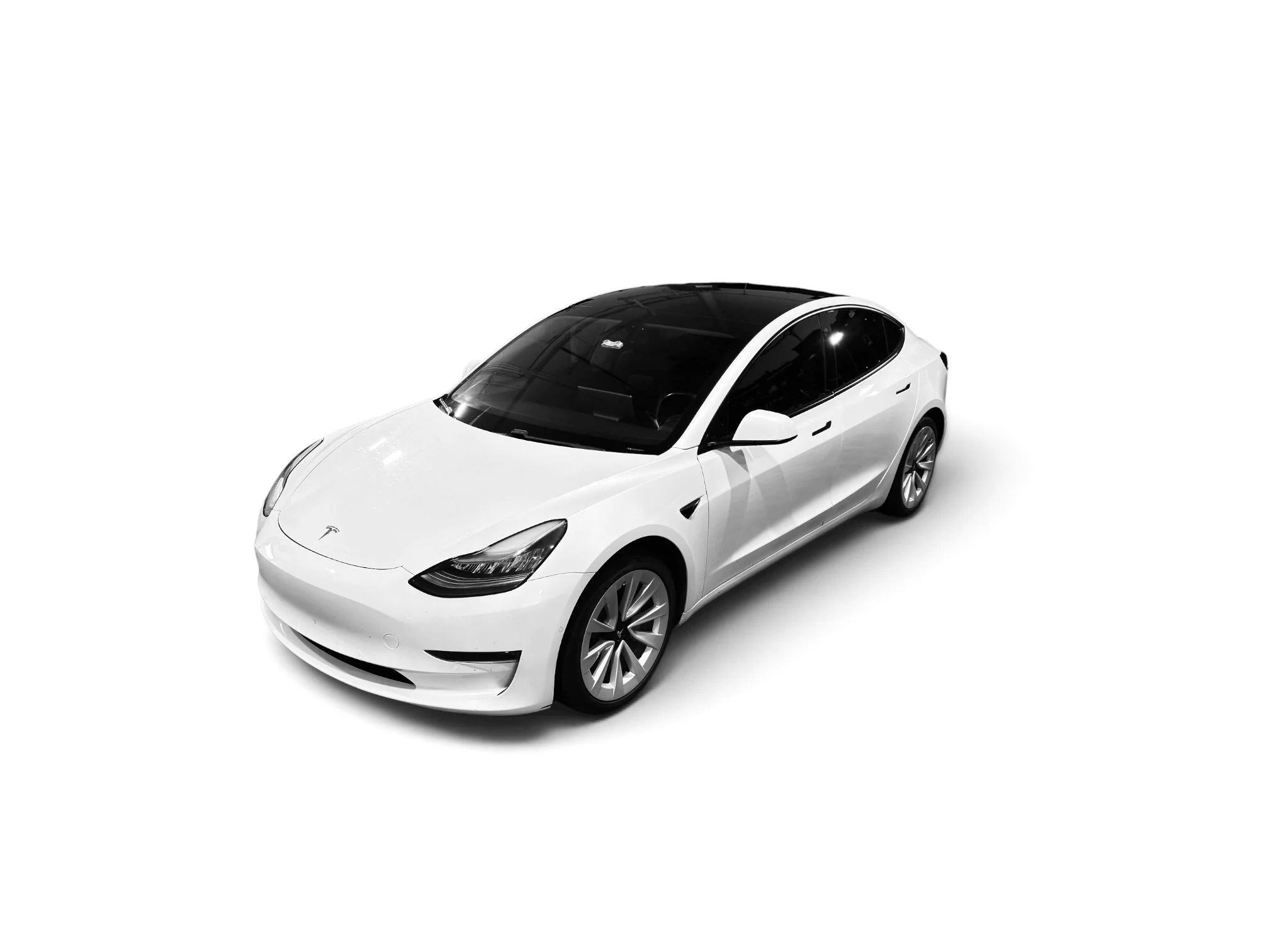 A white Tesla Model 3 electric car with a black roof, viewed from an elevated front angle.