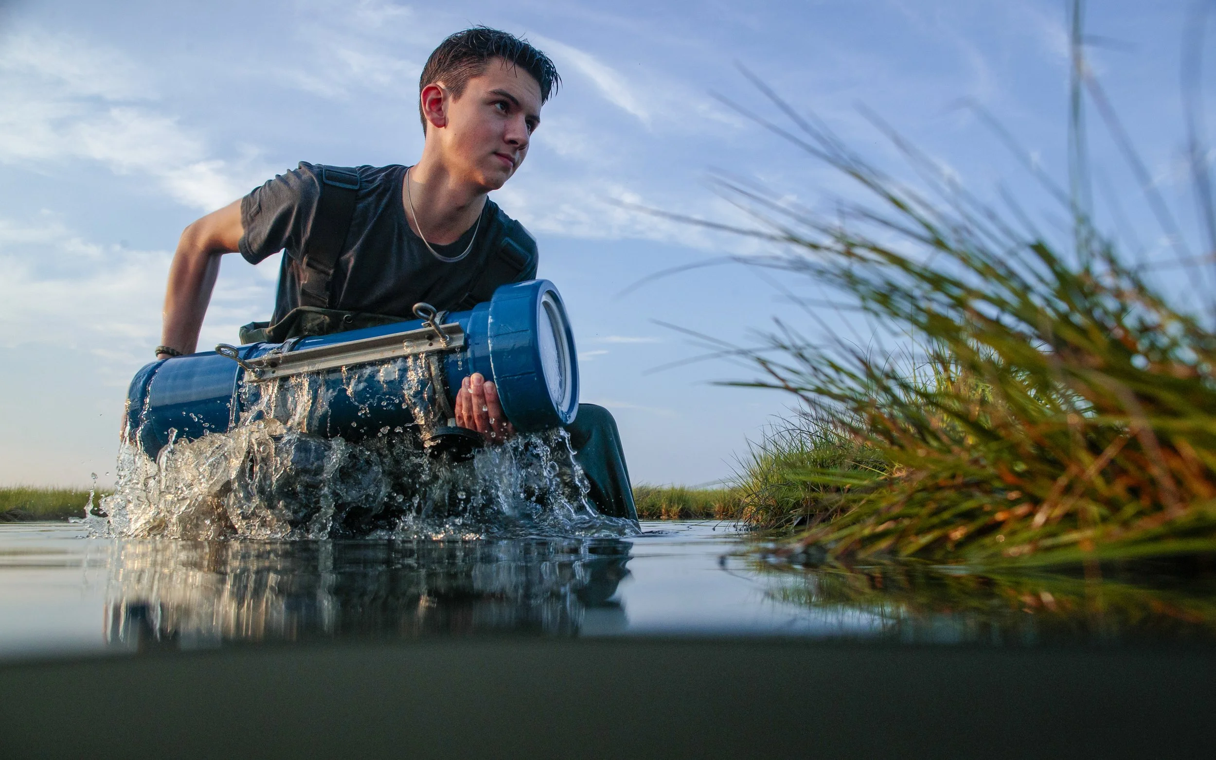 National Geographic Explorer Soren Goldsmith holding a Terrapin 1 aquatic camera trap, or underwater trail camera, in a salt marsh in Massachusetts New England.