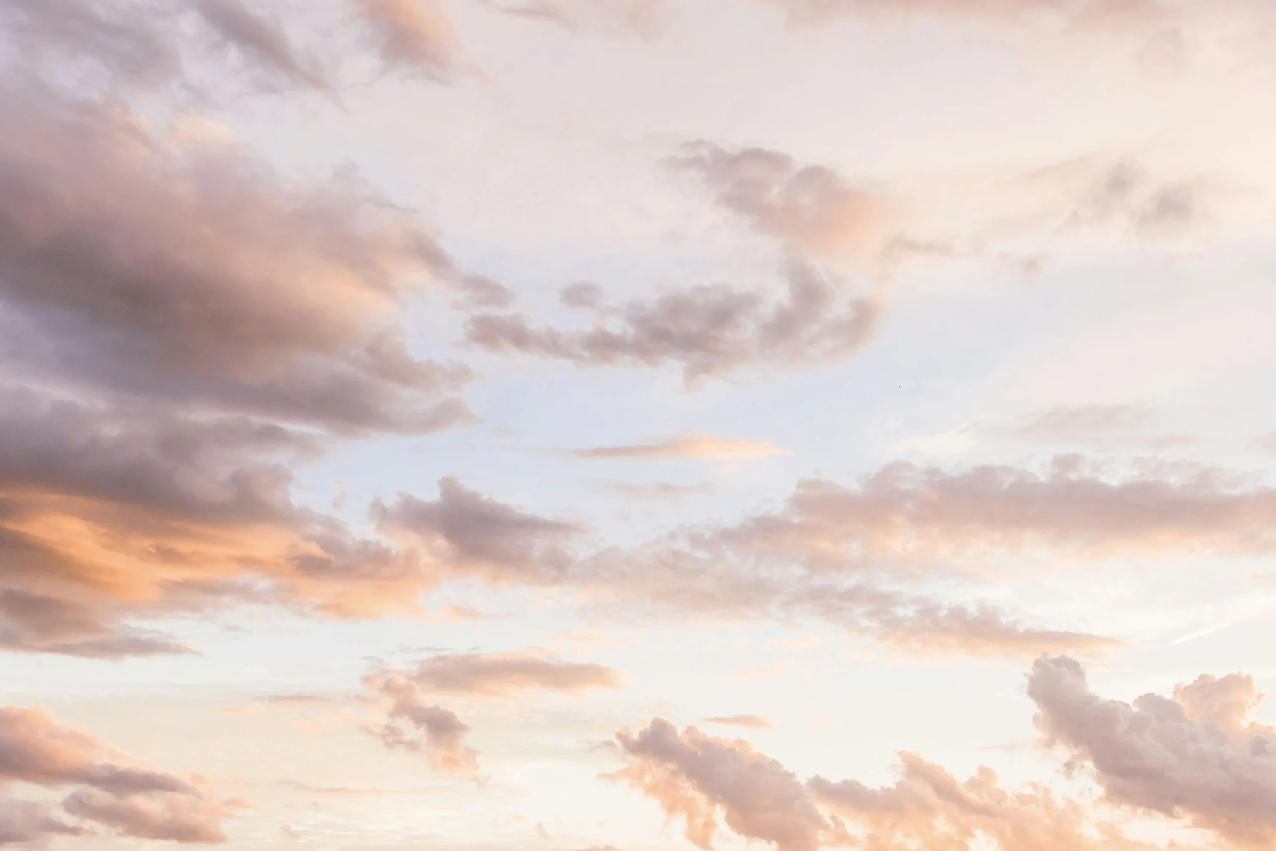 A sky with light pink and purple clouds during sunset or sunrise.