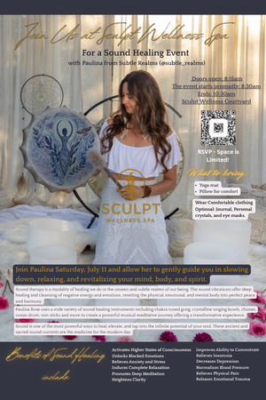 A woman with long brown hair, wearing a white top, holding a large spherical object with a blue and black design, in an indoor wellness event space with gold and white decor.
