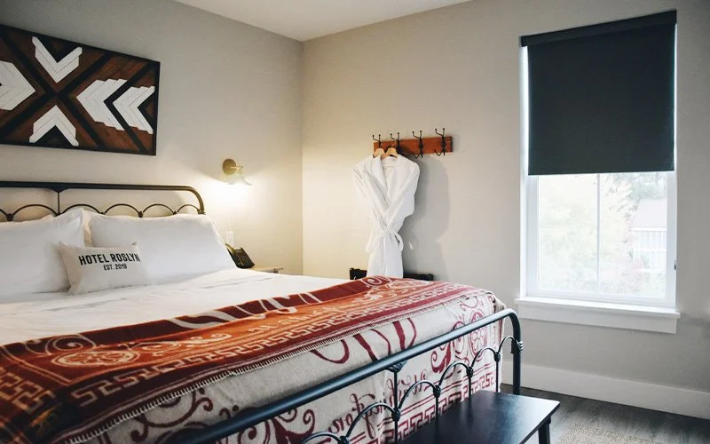 A hotel room with a bed, window, and robe