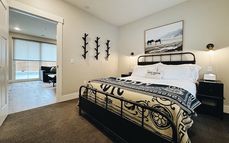 A hotel room with a bed, nightstand, and artwork
