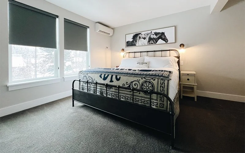 A wide view of a hotel room with a bed, window, and nightstand.