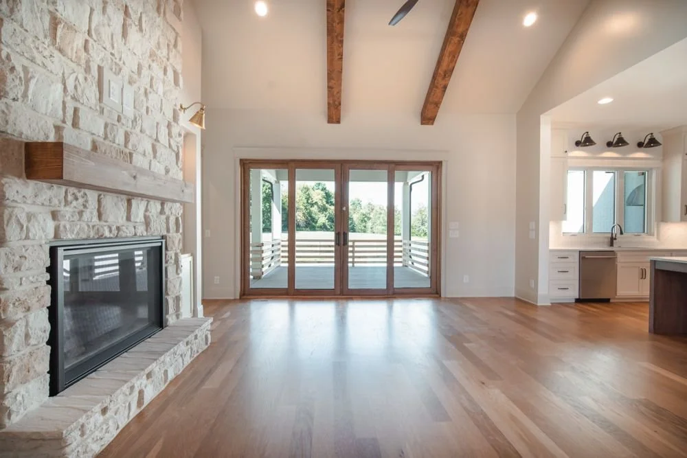 Stone fireplace with a wood mantel beside a wall of glass sliding doors