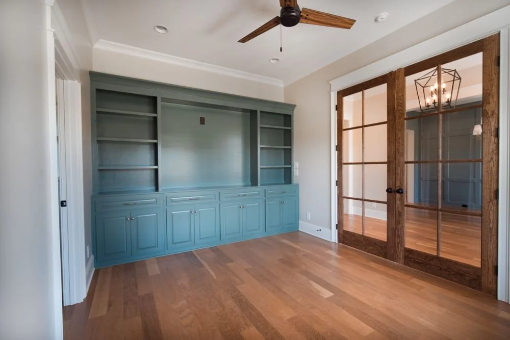 Room with blue-gray built-in cabinets and shelves and glass-paneled wood double doors