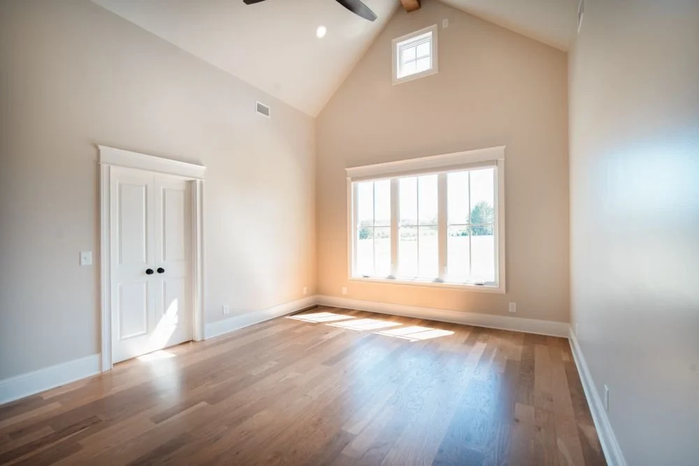 Bedroom with a vaulted ceiling, wood floors, a large window and a small upper window