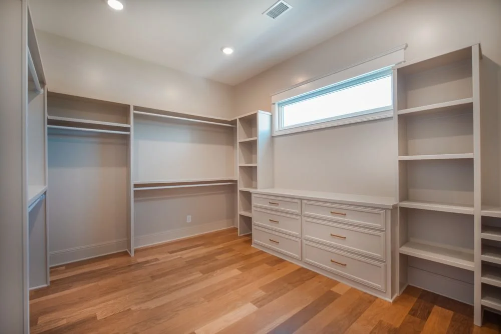 Walk-in closet with built-in shelves, hanging rods, drawers and a transom window