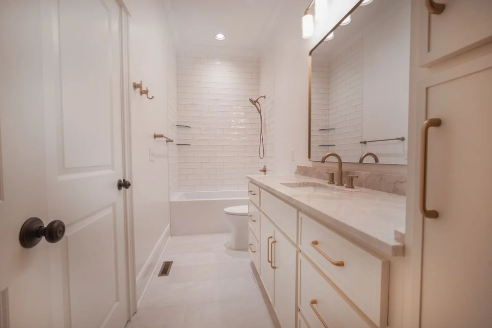 Bathroom with white cabinets, a tub and shower with white subway tile and a large mirror