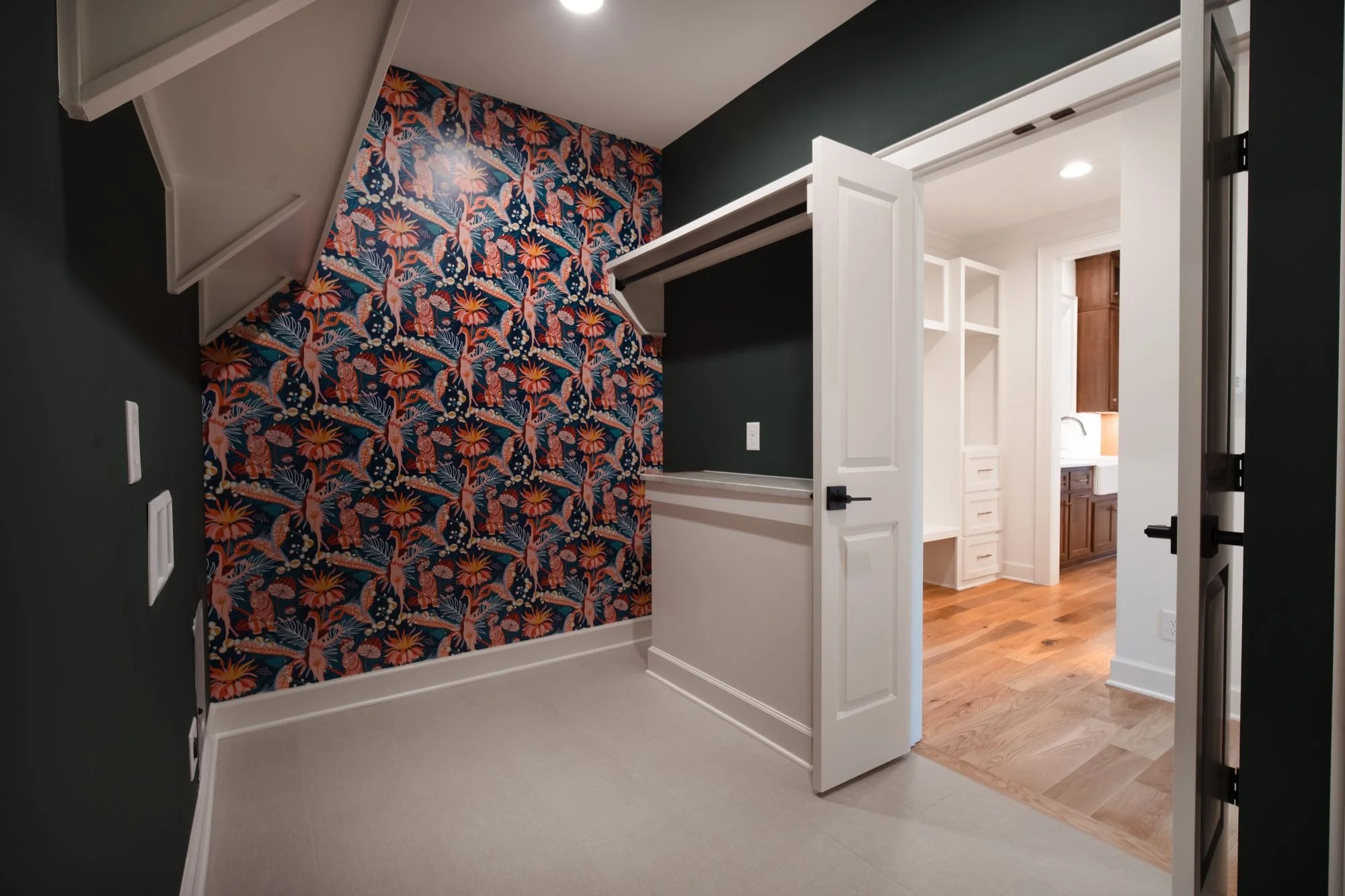 Small room with bold floral wallpaper on one wall and dark green walls