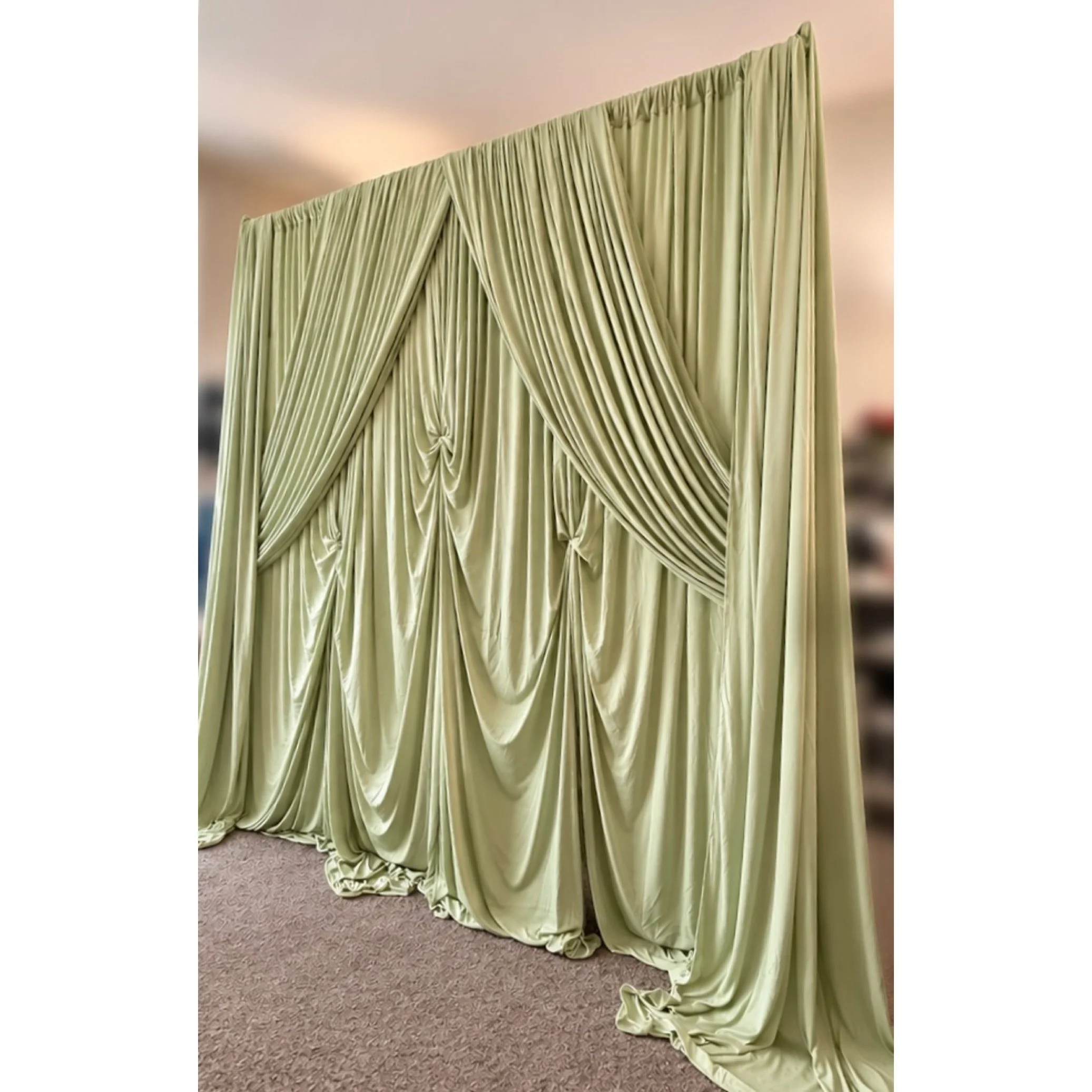 Luxurious sage‑green event draping featuring layered swags and soft gathered folds, creating an elegant backdrop perfect for weddings, showers, and photo moments. This premium fabric setup adds a romantic, high‑end touch to any venue and pairs beauti