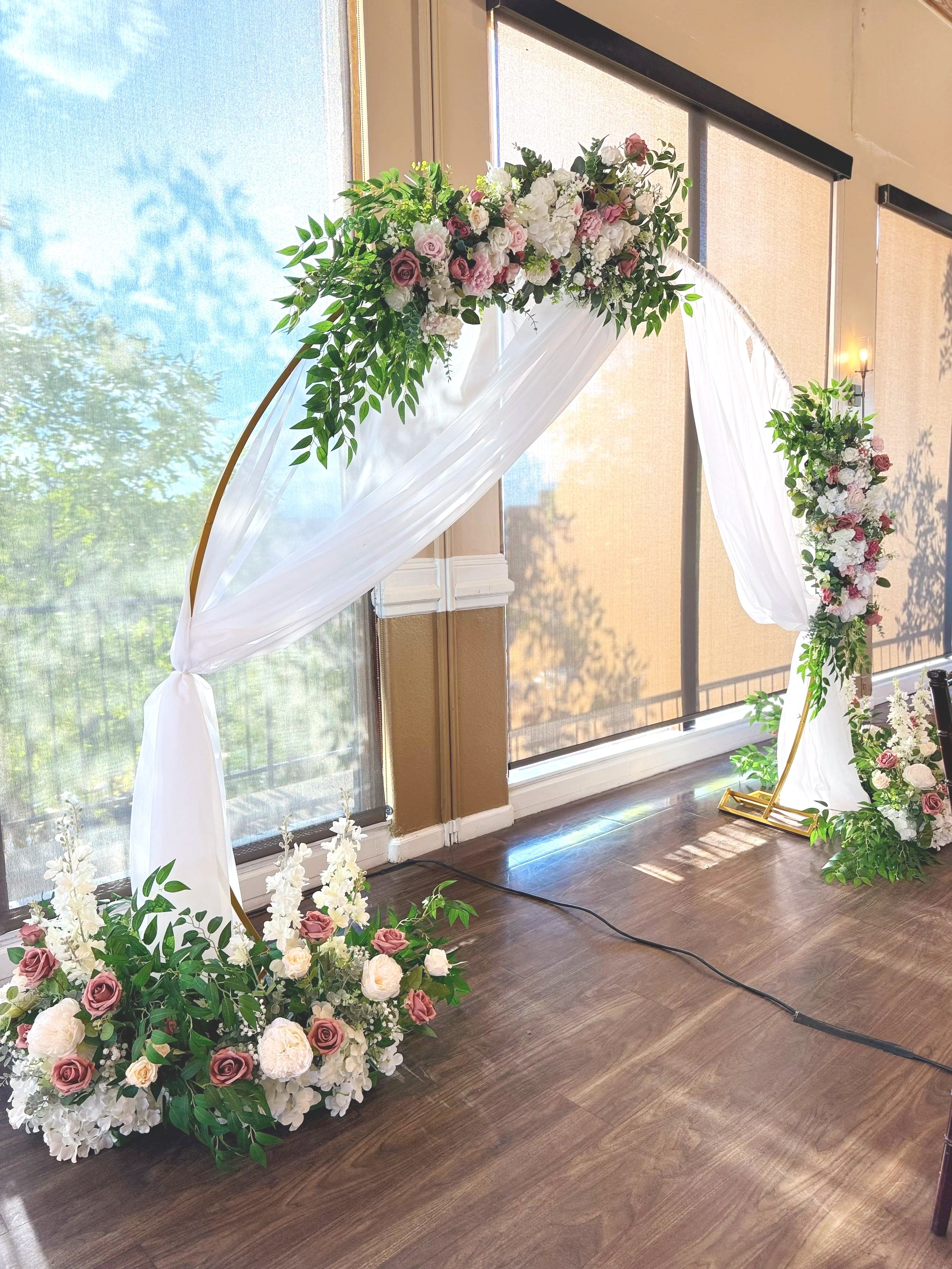 Round arch with white draping and florals on a Colorado dance floor