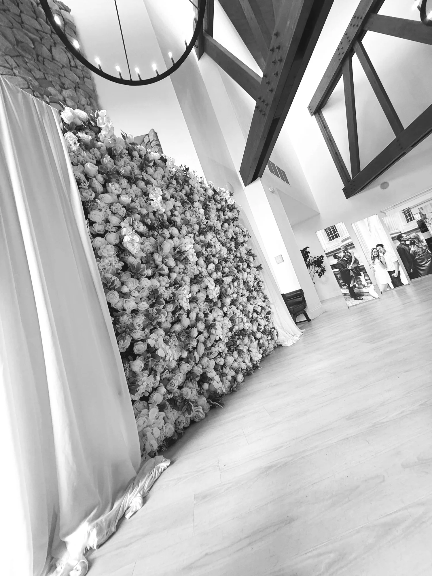 Large floral backdrop covered in roses with draped fabric at an indoor event space