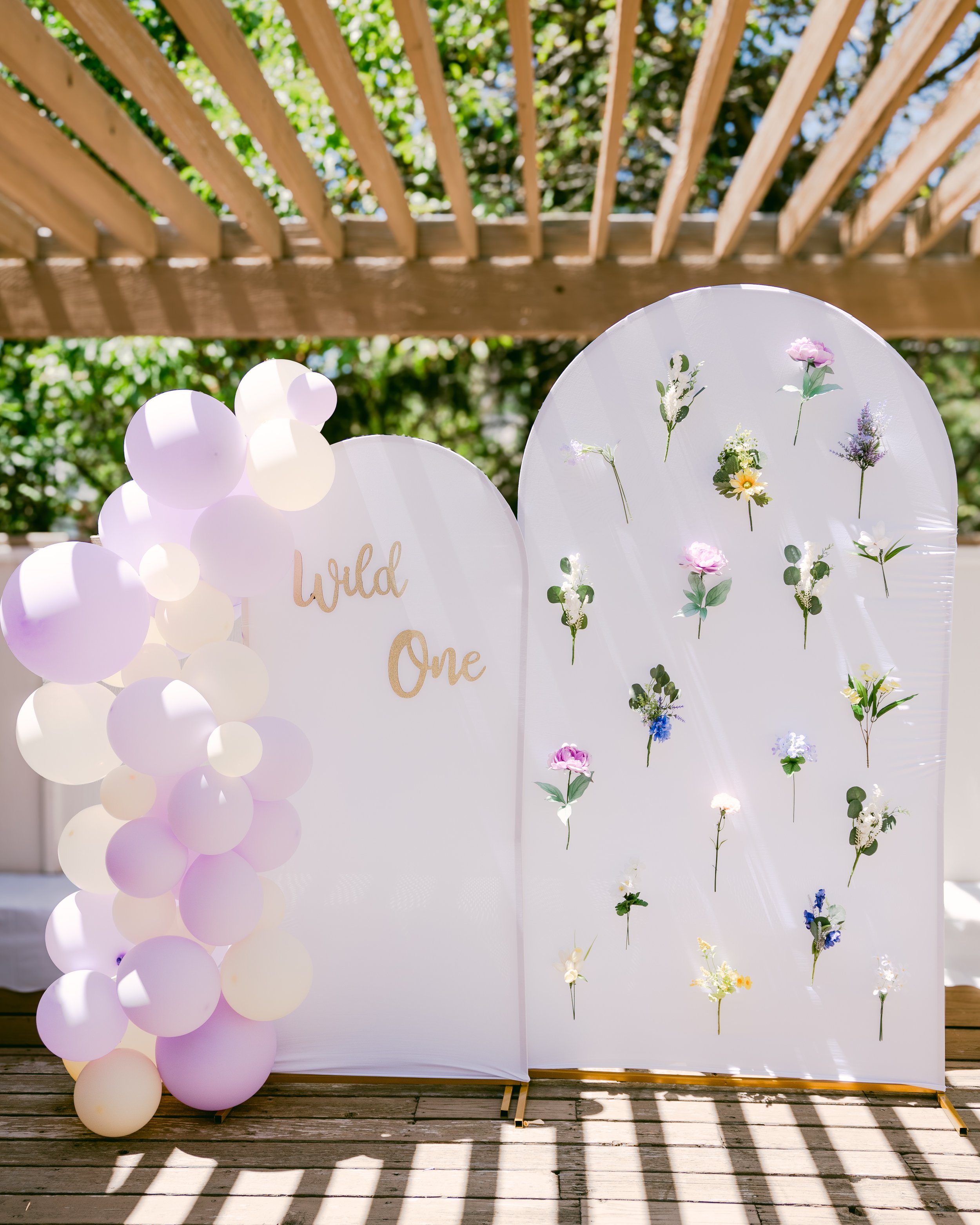 White arch with lilac balloon garland and pressed florals in Colorado